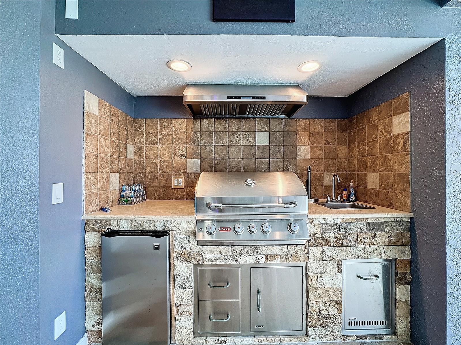 Beautiful outdoor kitchen with Bull BBQ and exhaust vent, fridge and storage