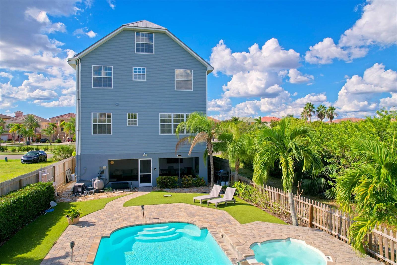 View of back of home from pool - lower level is an enclosed and screen lanai great for entertaining!