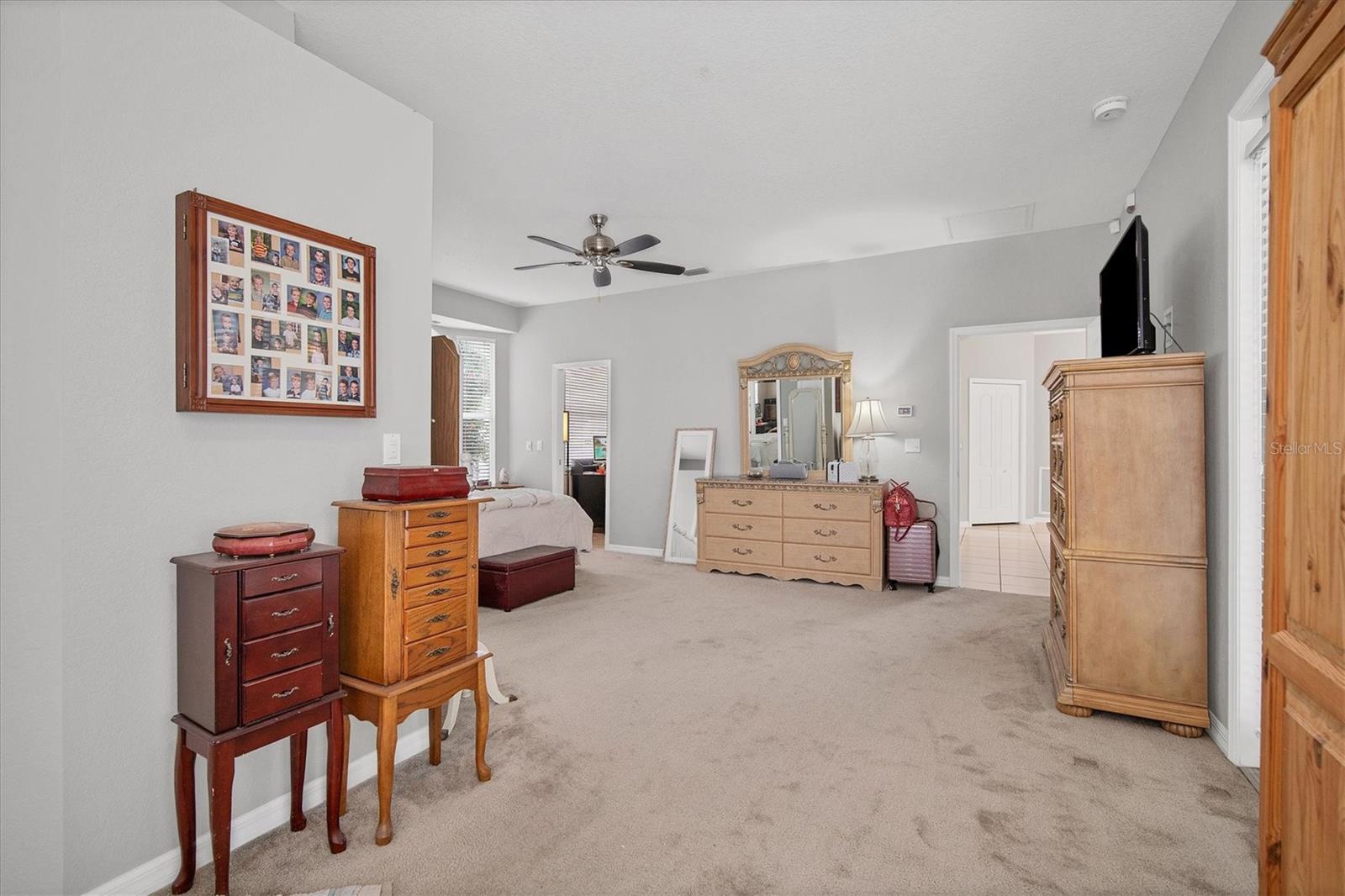 View of master bedroom from sitting area.  Hallway leads to adjacent bedroom, laundry room & garage.