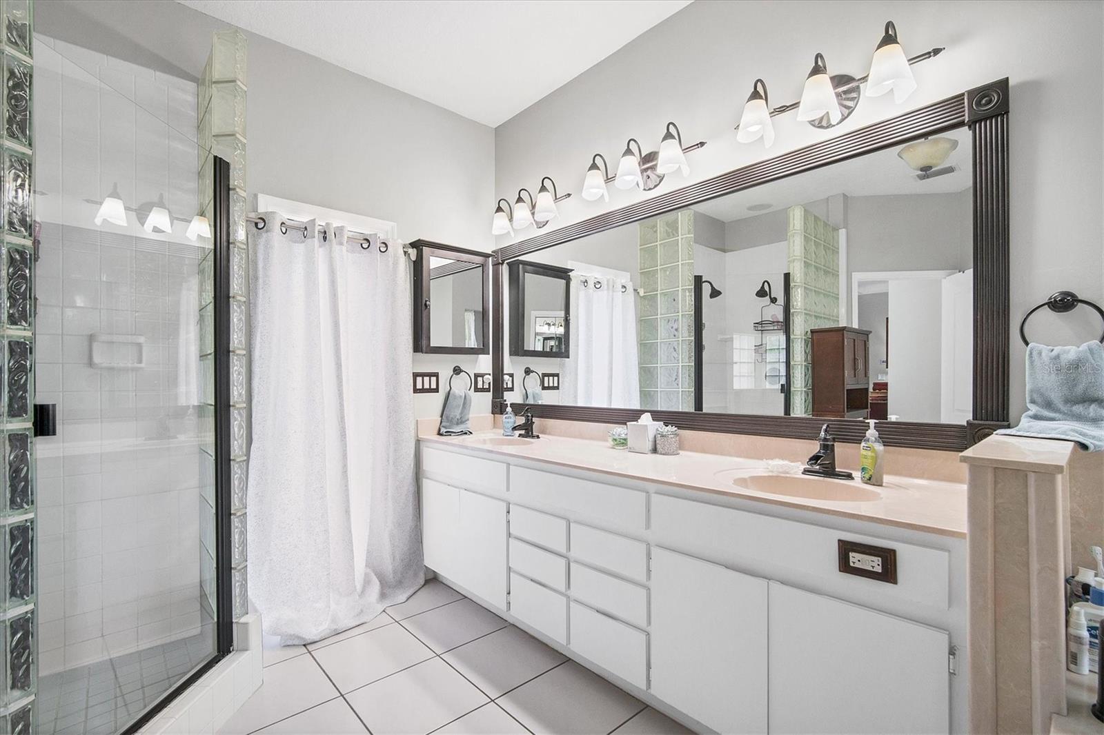 Master bathroom offers dual vanities with ample storage, a door to pool/patio and a walk in shower.