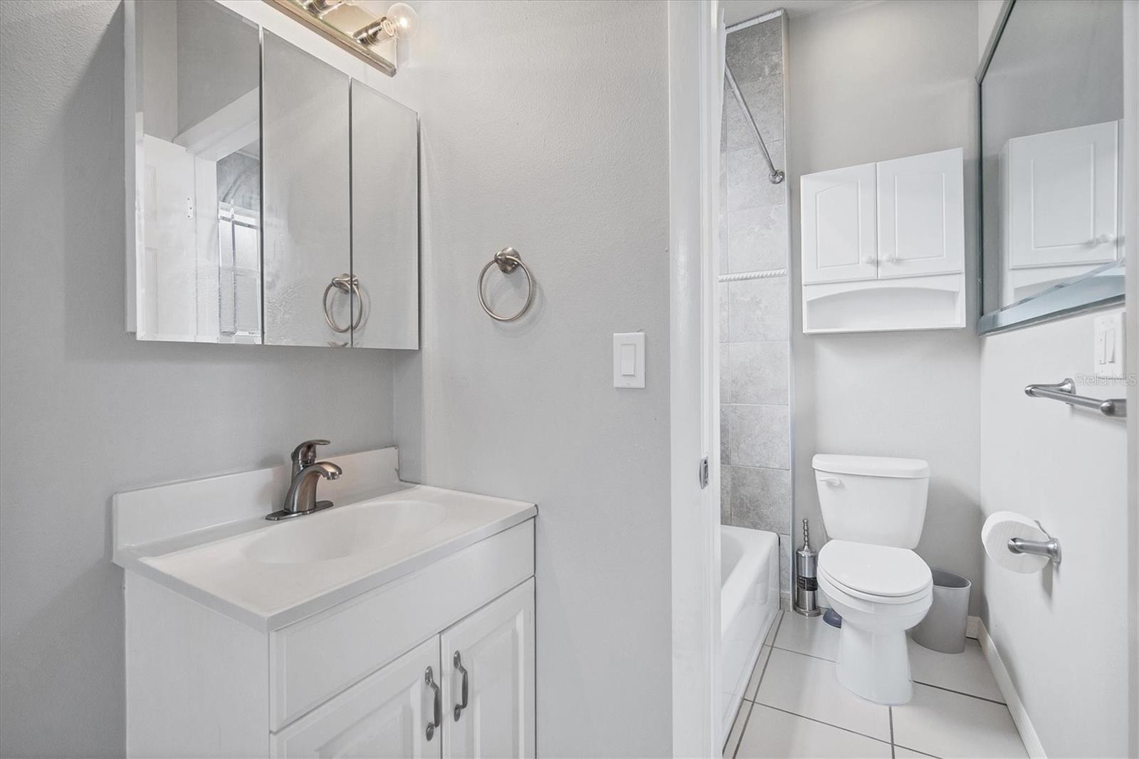 Vanity and cabinet just outside the room including a tub/shower combo and toilet