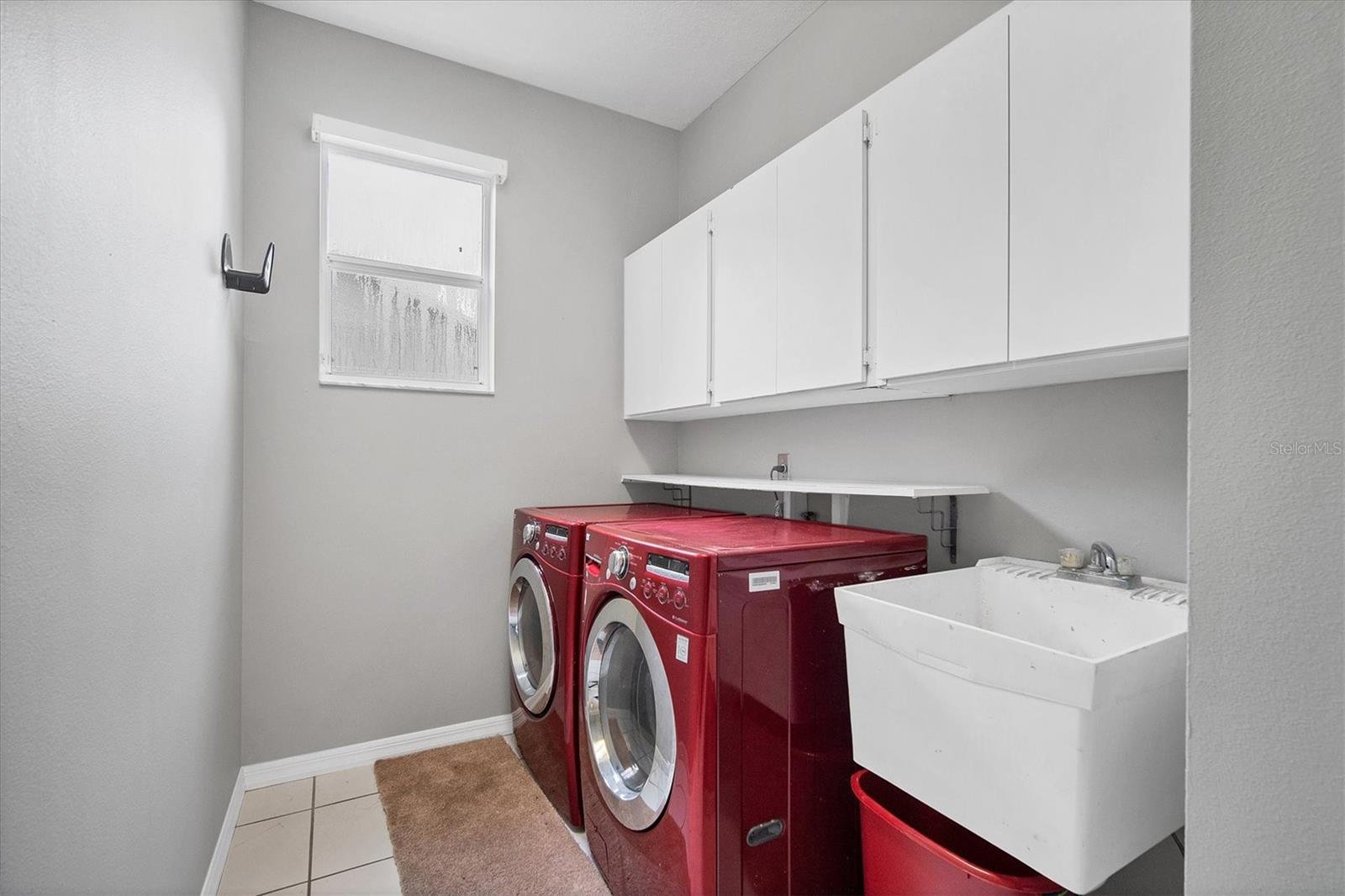 Large laundry room with full size front load washer and dryer plus utility sink, storage cabinets and closet!