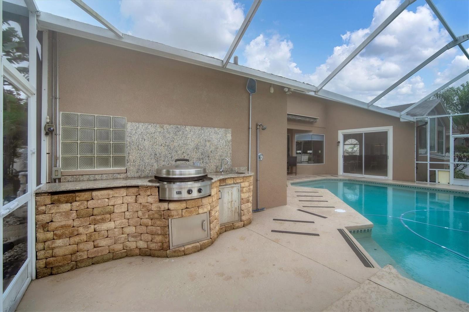 Outdoor grilling area features granite countertop for food prep and has a convenient sink too!  Handy shower to rinse off after working in yard or before & after using pool.