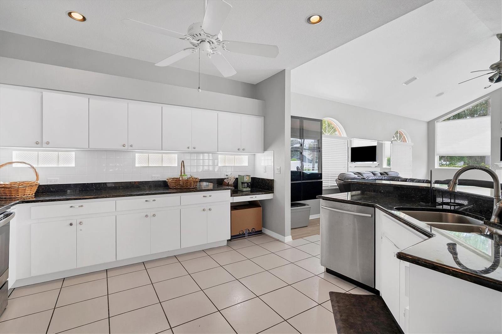 Roomy kitchen equipped with lots of cabinets, a built in desk & granite countertops.