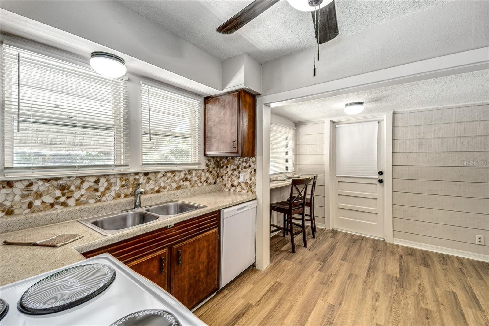 Large kitchen with stone backsplash and original solid wood cabinetry...door at end is entrance to rear garage