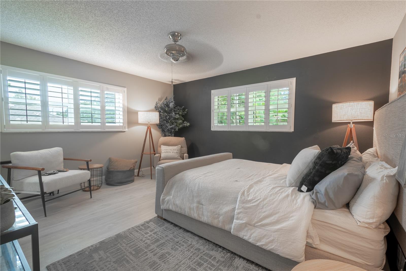 The primary bedroom features two large, hurricane and wind resistant windows with NEW plantation shutters, wood laminate flooring and a ceiling fan.