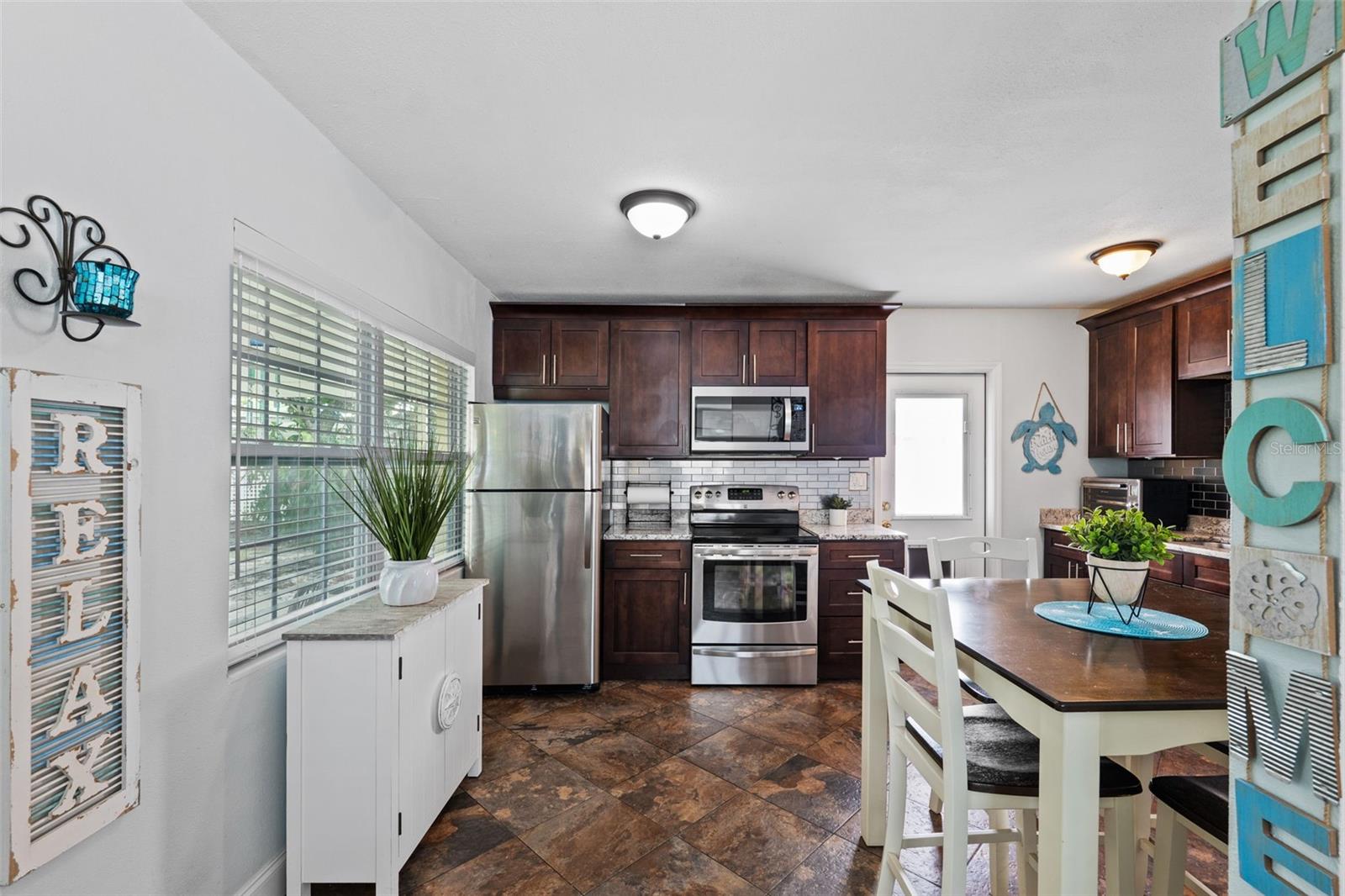 Lovely eat-in kitchen with stainless appliances, granite counters, and stainless steel tiles for a backsplash