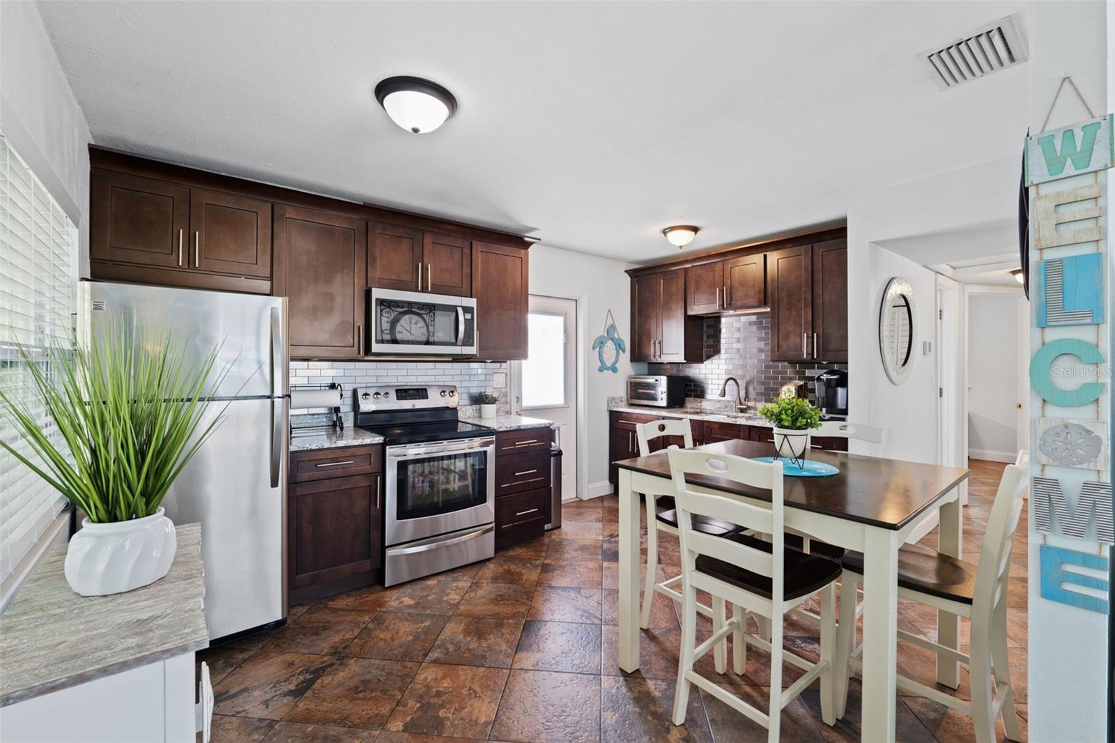 Lovely eat-in kitchen with stainless appliances, granite counters, and stainless steel tiles for a backsplash