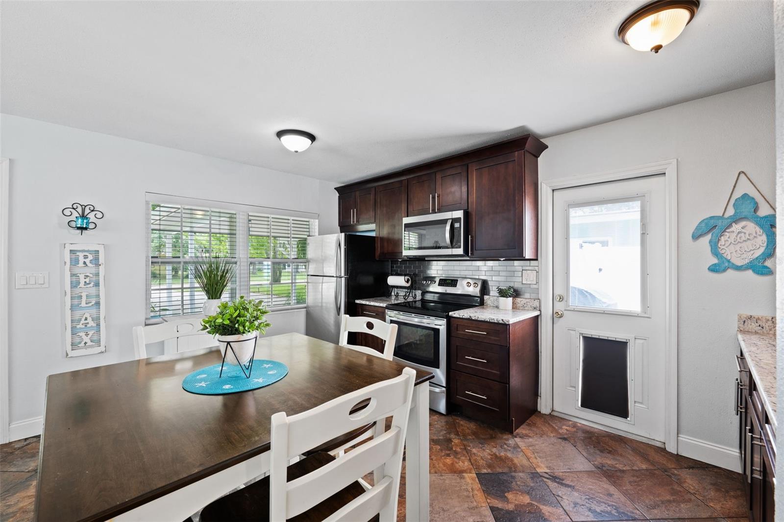 Lovely eat-in kitchen with stainless appliances, granite counters, and stainless steel tiles for a backsplash. The side door leads out to your private paver patio and fire pit.