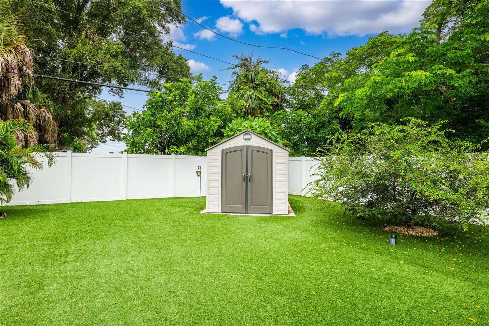 Pet-friendly turf, vinyl privacy fence, and storage shed make for a well-equipped rear lawn.