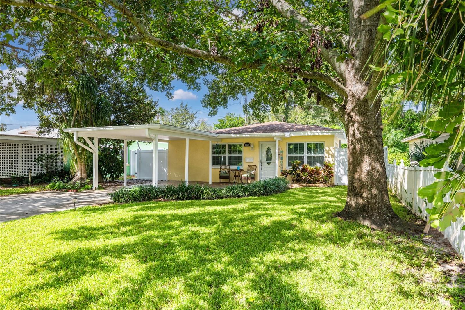 This lovely cottage home is tucked under the dappled shade of a beautiful, mature tree and framed by a lush lawn.