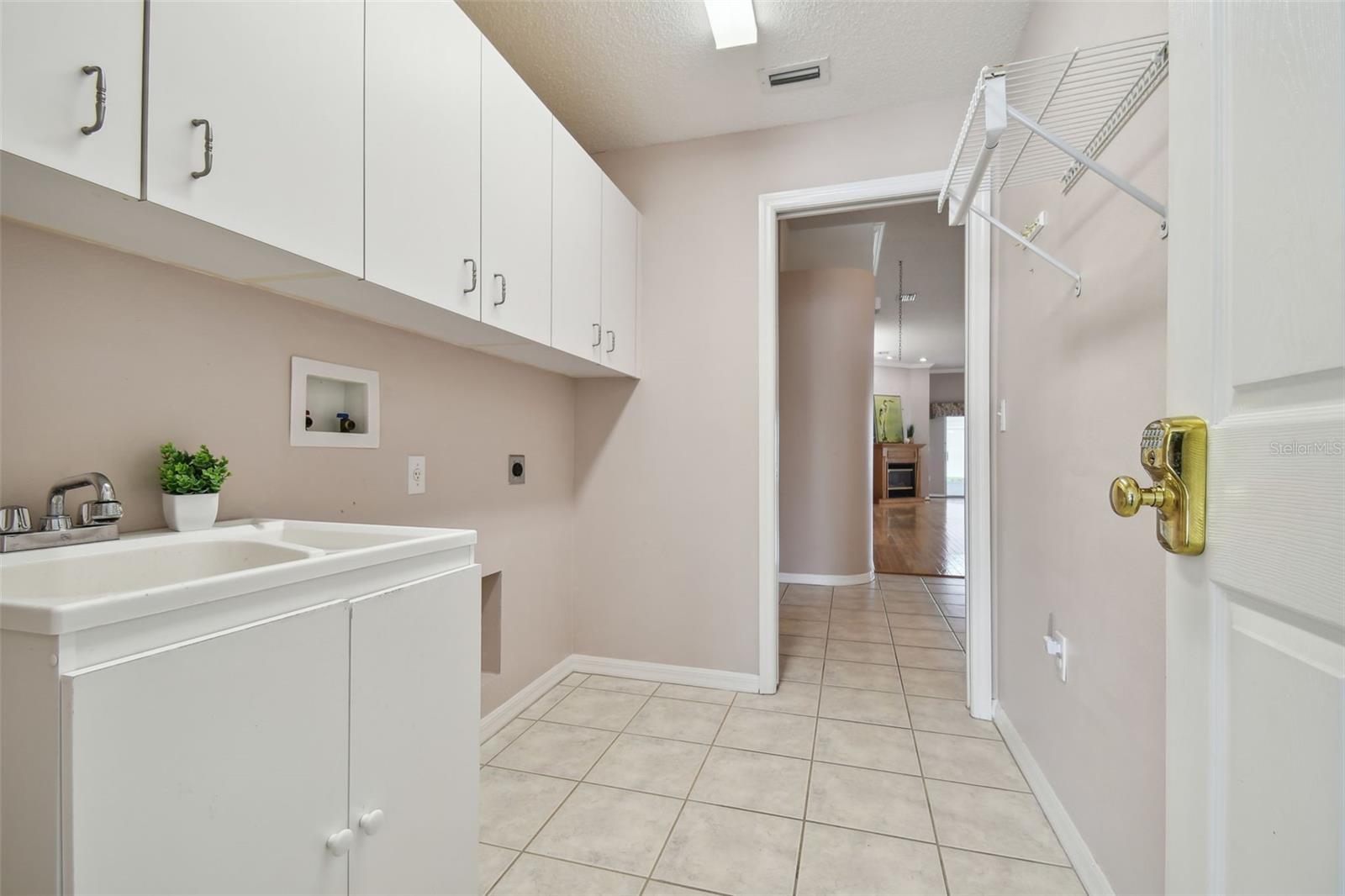 inside laundry room with utility sink and loads of cabinets