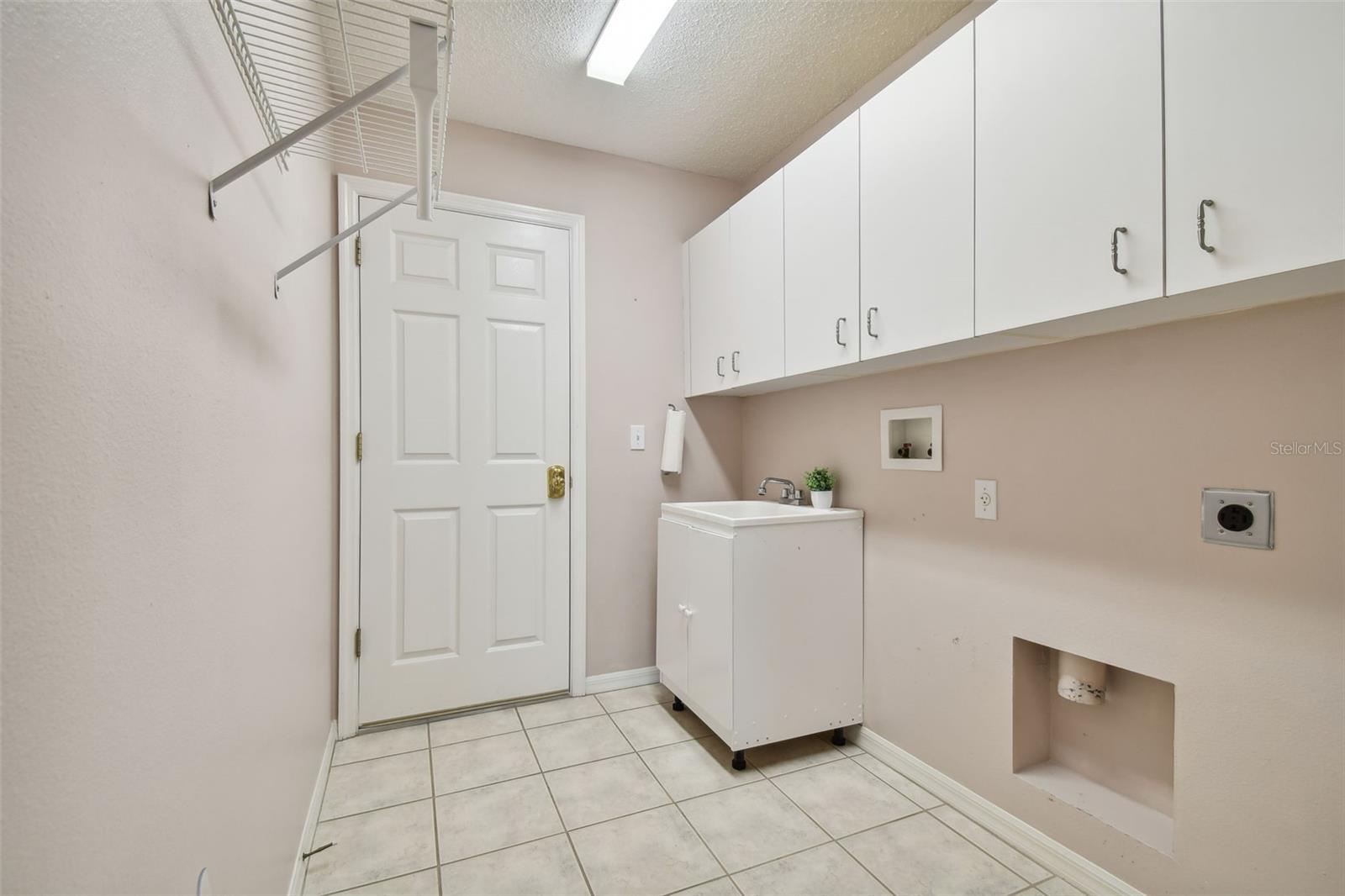 inside laundry room with utility sink and loads of storage with cabinets