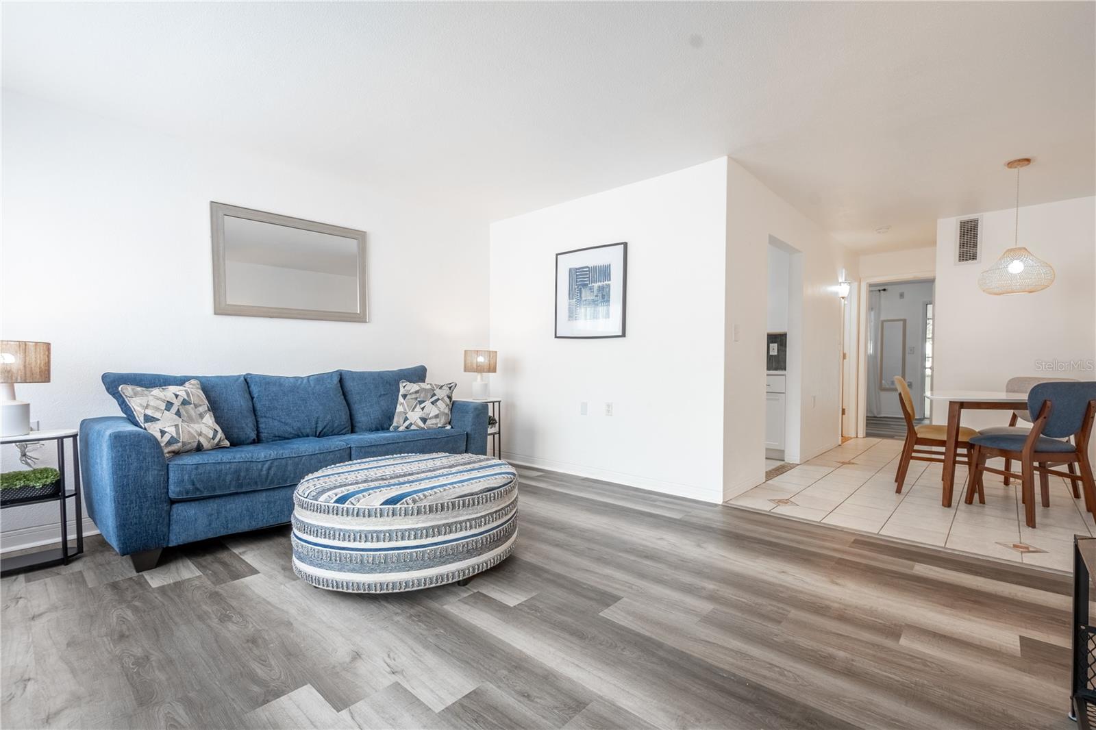 Open and airy living room, bathed in neutral tones with wood laminate flooring.