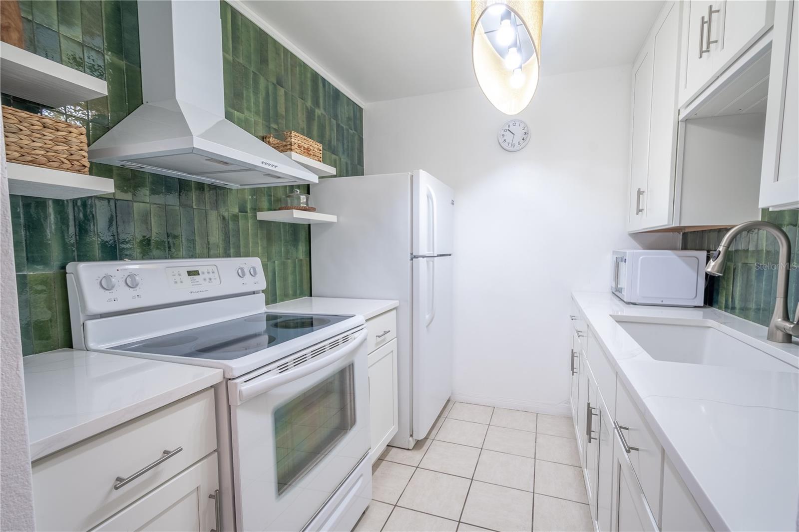 The galley kitchen features a decorative tile backsplash and ceramic tile floor.