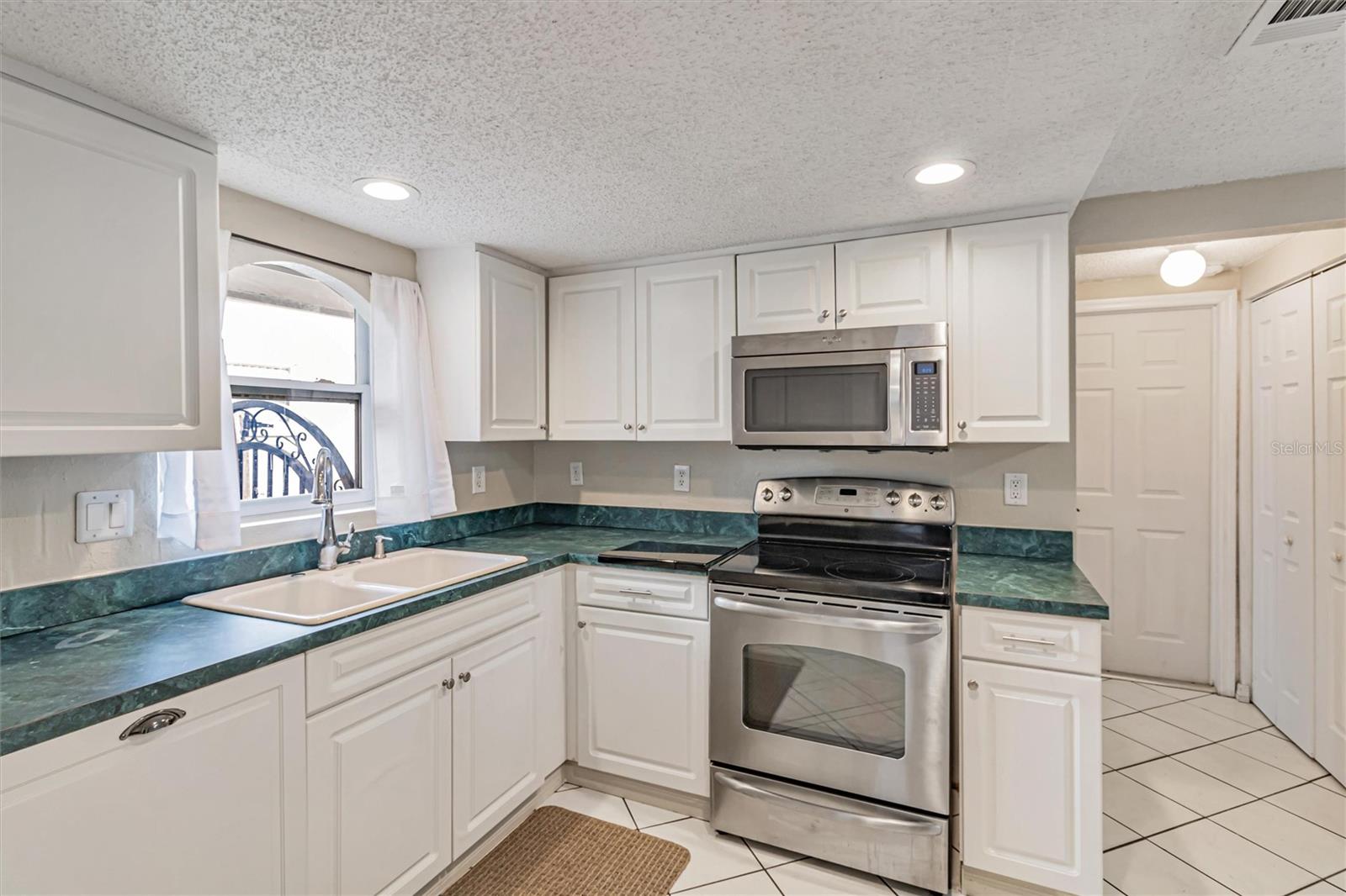 Kitchen includes a paneled dishwasher. Utility closet to the right of the door which leads to the garage. Second bathroom is located opposite the utility closet.