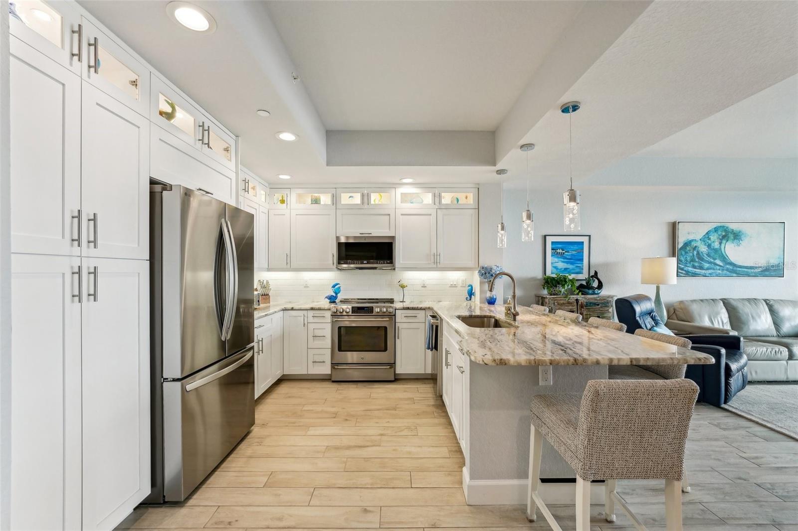 Spacious designer kitchen with large peninsula and custom lighted display nooks above each cabinet.  Notice the tray ceiling which is another classy touch!