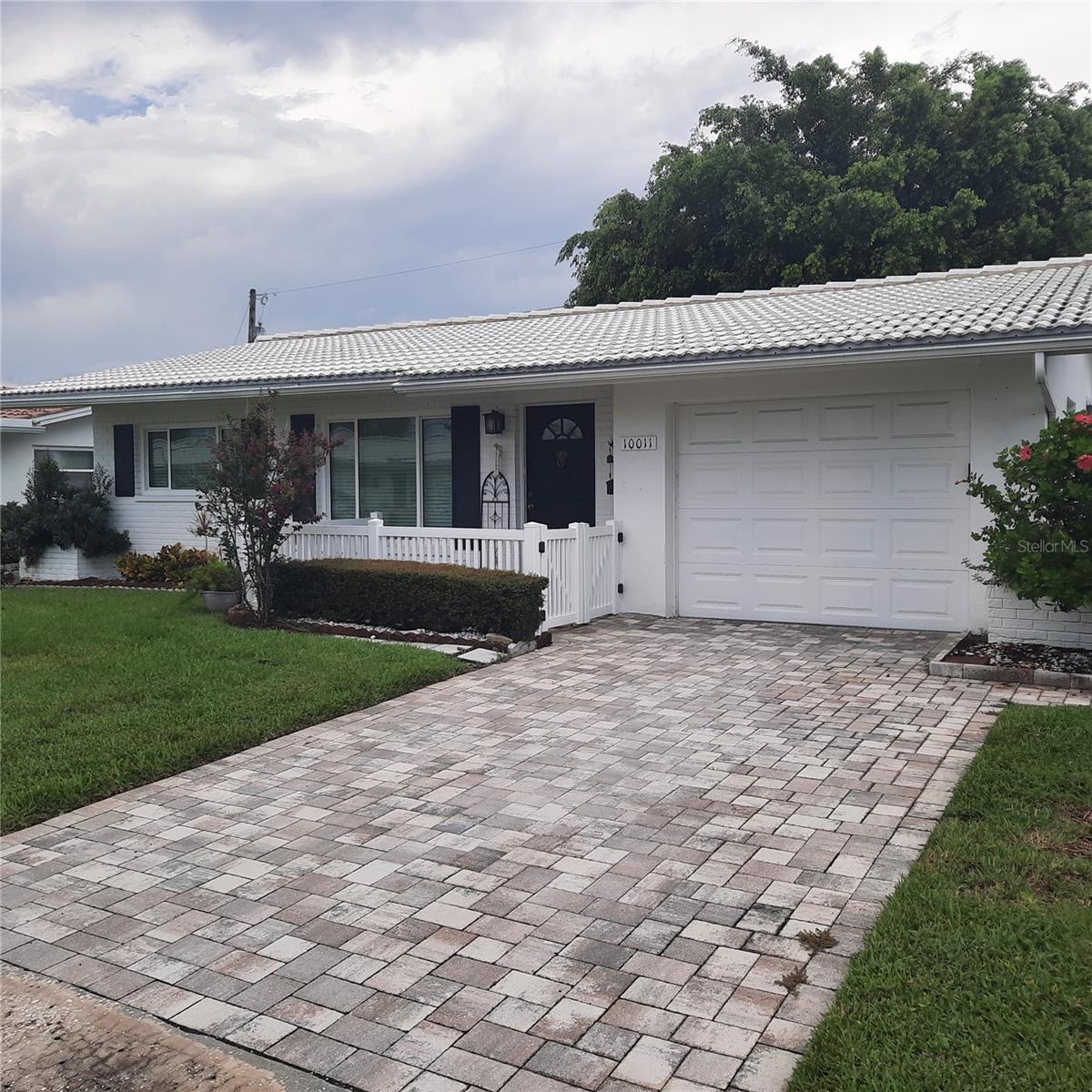 Paver brick driveway with fenced porch area.