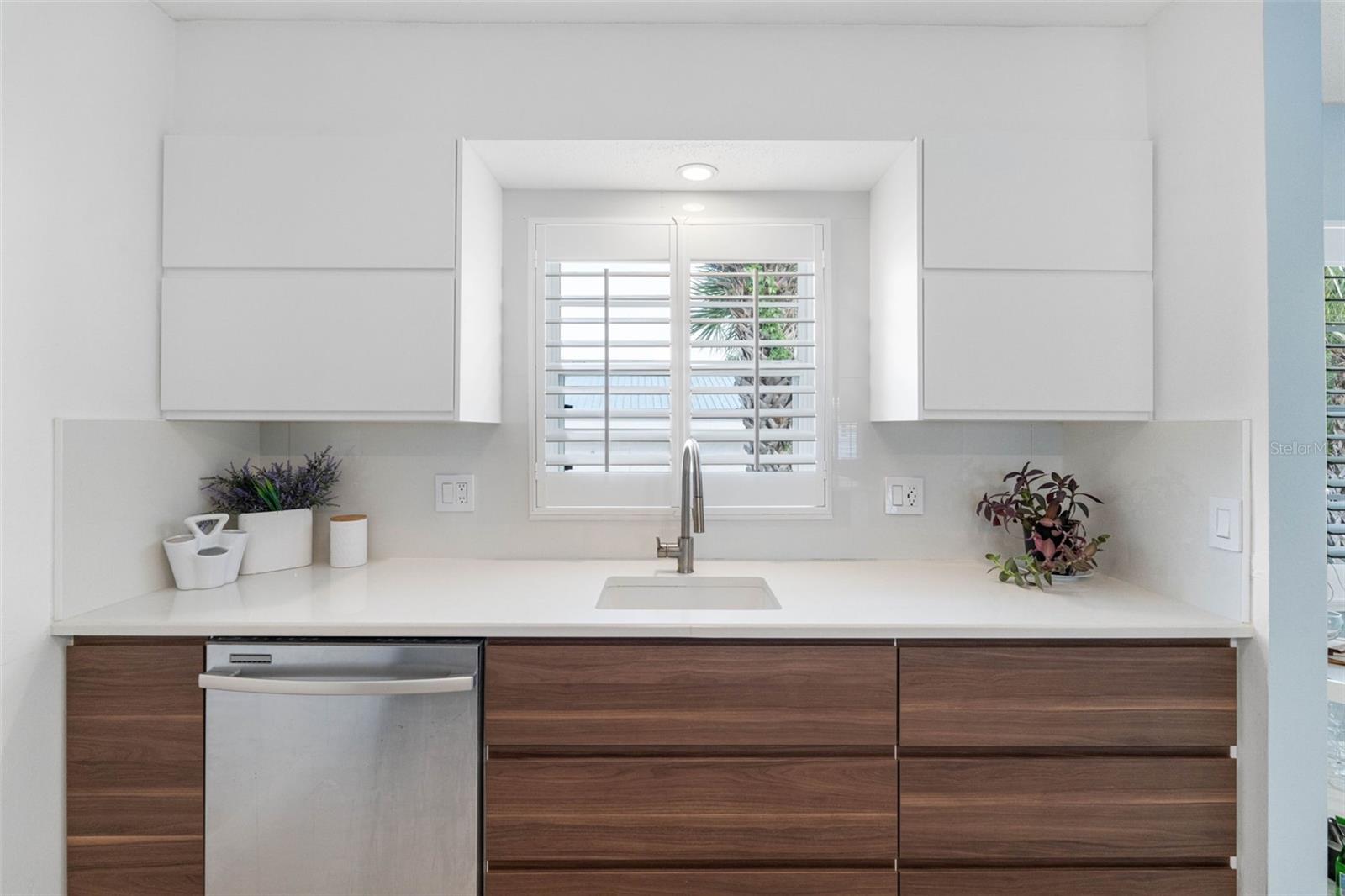 The large, single-basin sink situated beneath a wide window allows natural light to brighten the space, enhancing the clean lines and uncluttered feel.