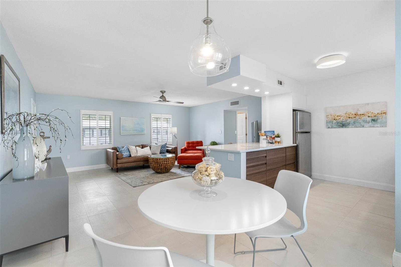 Adjacent to the living area, a sleek and modern kitchen with bar seating allows for easy conversation and interaction between the spaces.