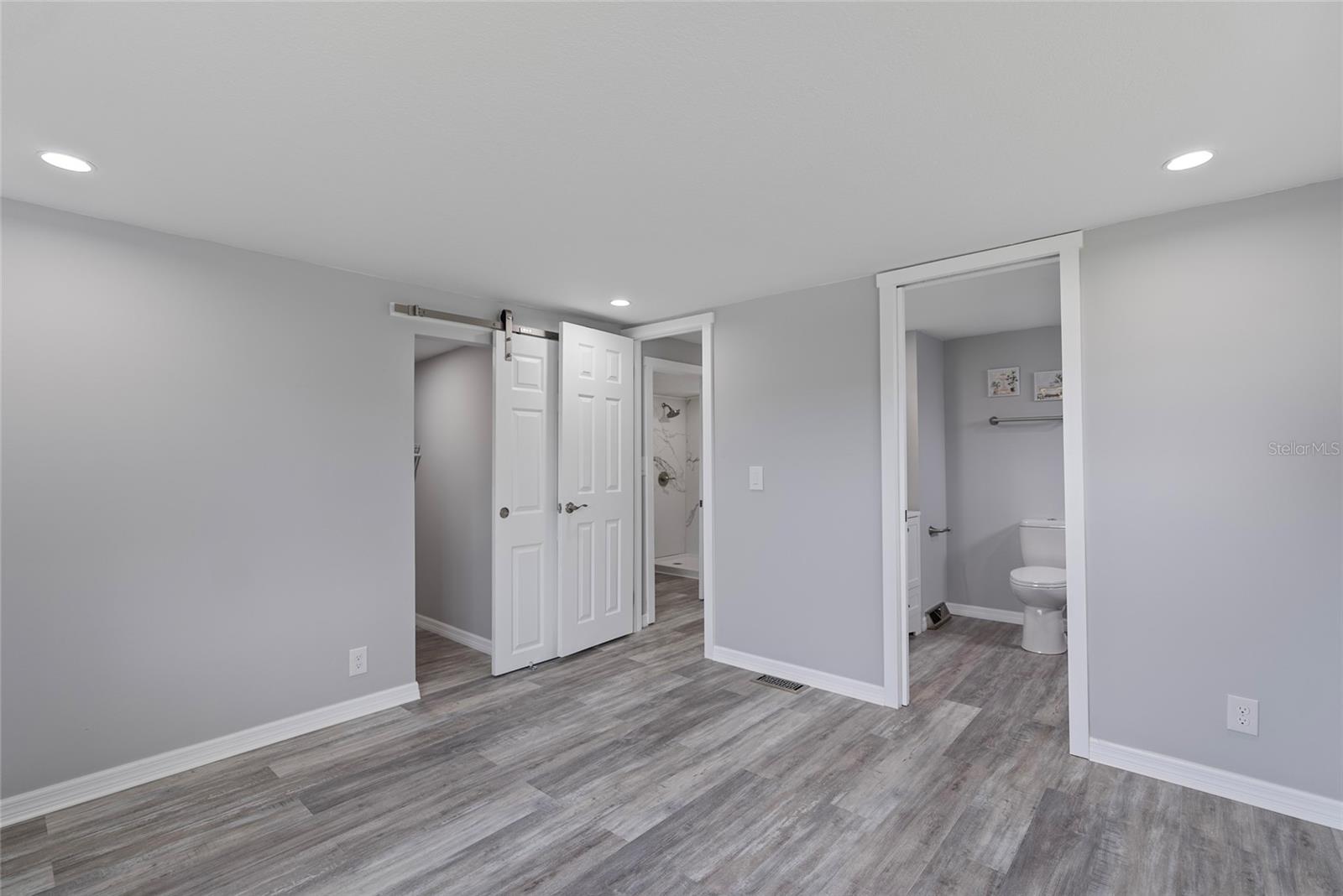 Primary bedroom with barn door slider to walkin closet