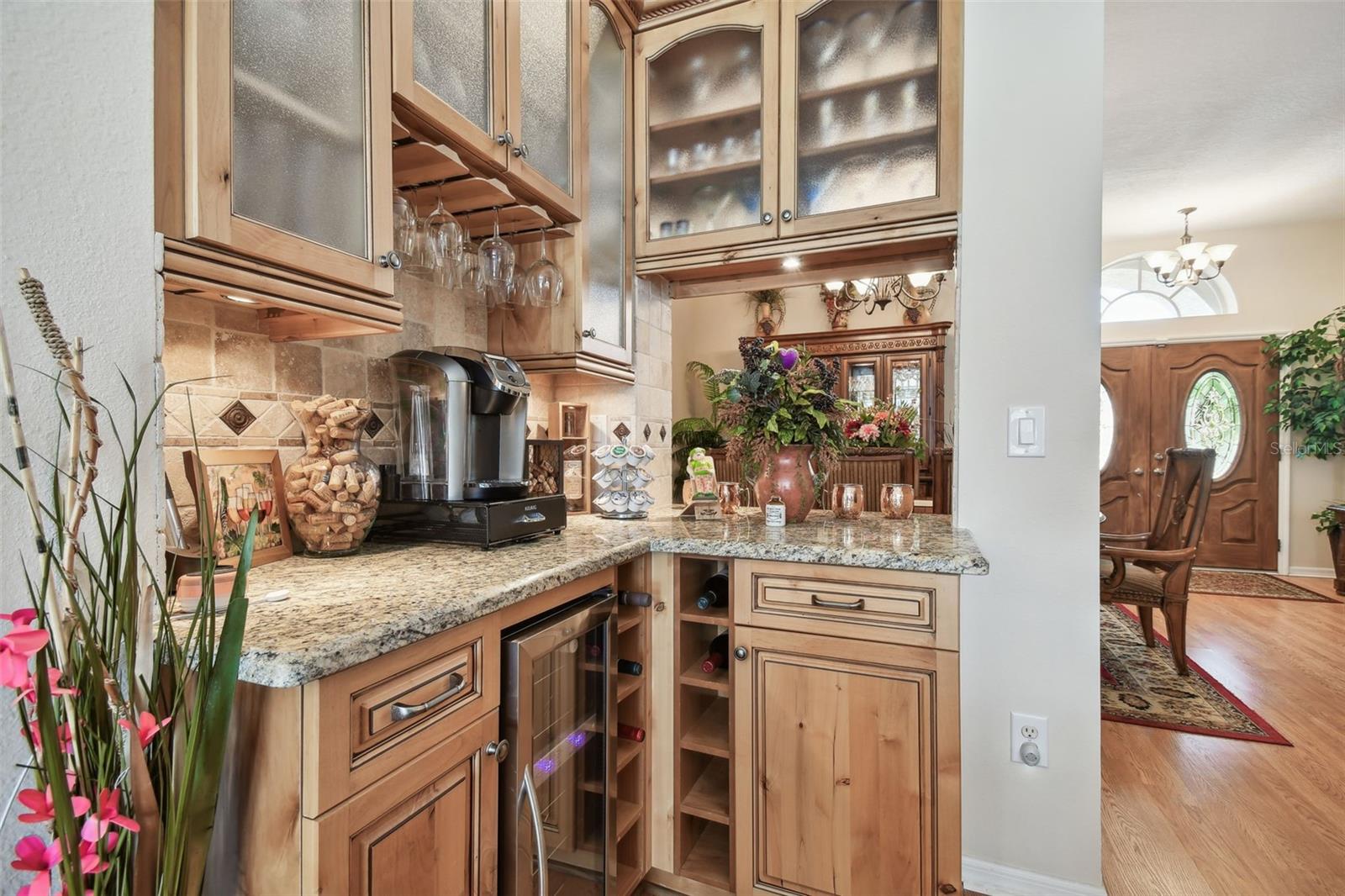 A sleek granite counter bar with built-in shelving & cabinets, wine cooler, stemware rack, perfect for a coffee station that combines functionality with elegance.