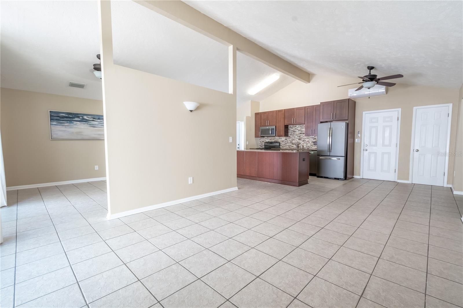 The dining room features a wall sconce, neutral tones, ceramic tile floor and vaulted ceiling.