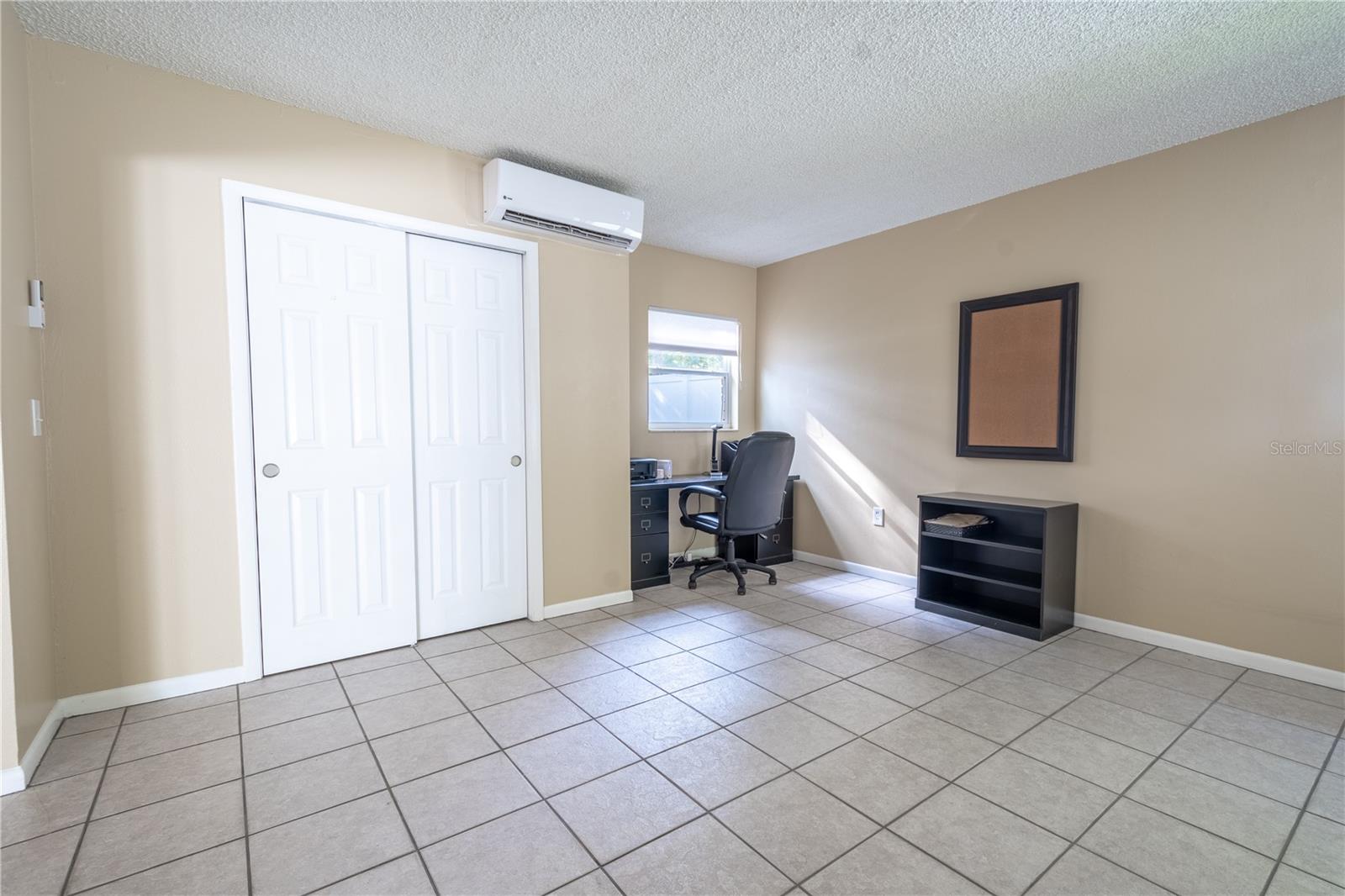 The family room features a built in closet, a mini split for added comfort, a neutral color palette and ceramic tile floor.