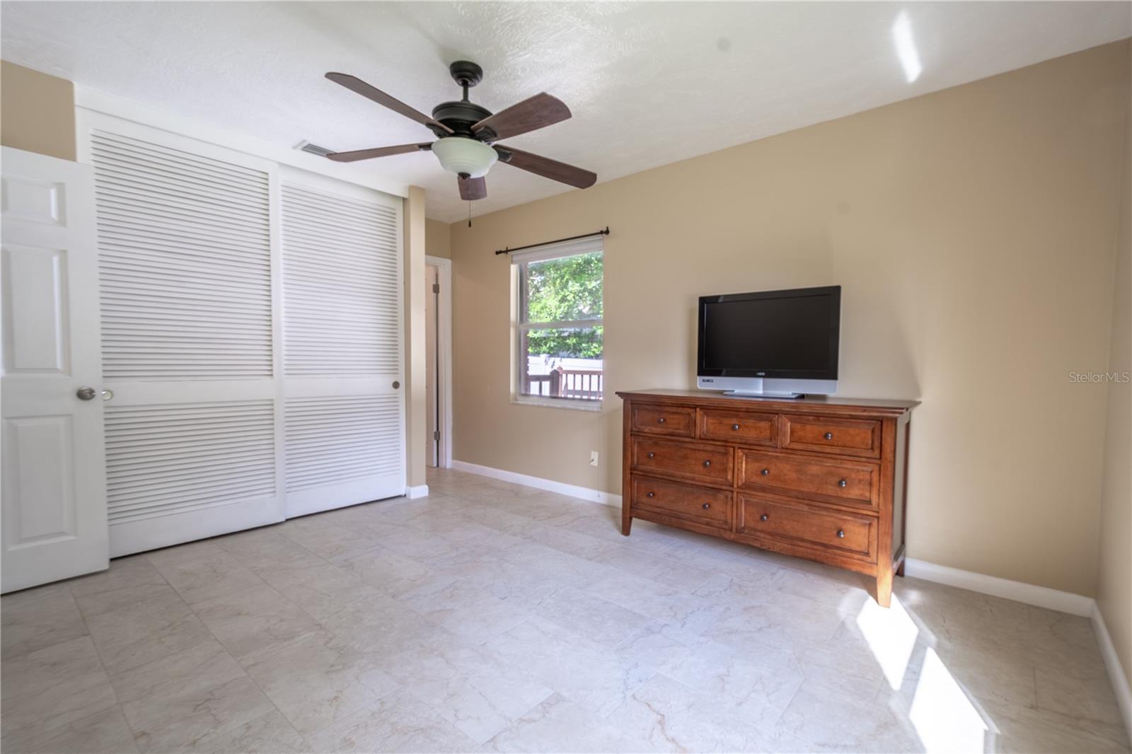 The Primary Bedroom features neutral tones, a built-in closet and a ceiling fan with light kit.