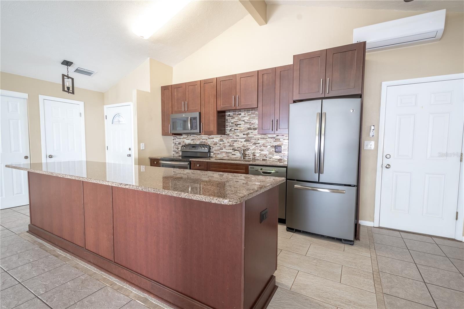 The kitchen features ceramic tile flooring and vaulted ceiling.