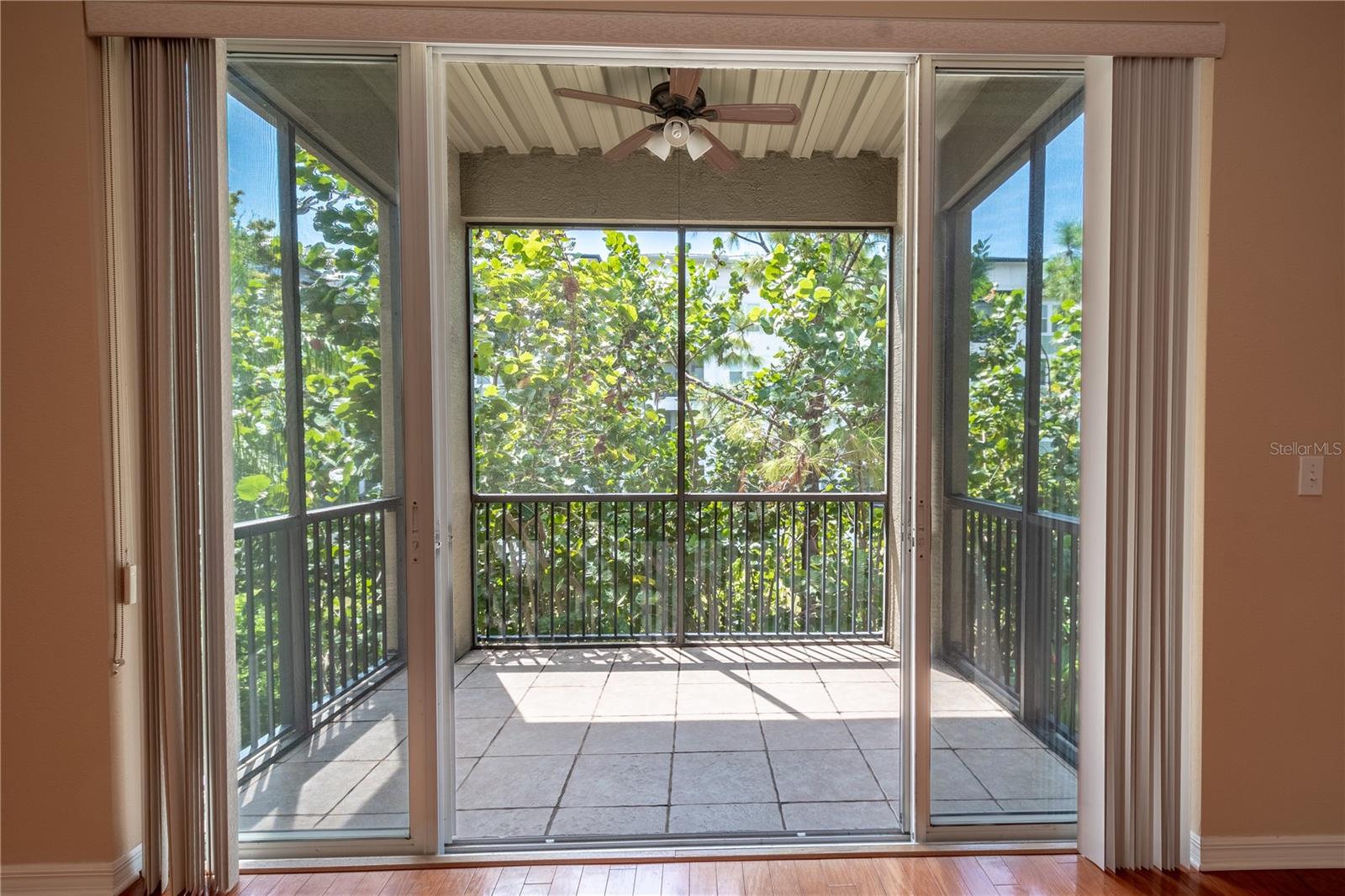 Step out onto the covered, screened-in balcony just off the main living area—a perfect spot to unwind. With its tiled floor and ceiling fan with a light kit, it's ideal for enjoying fresh air and peaceful evenings, no matter the season.