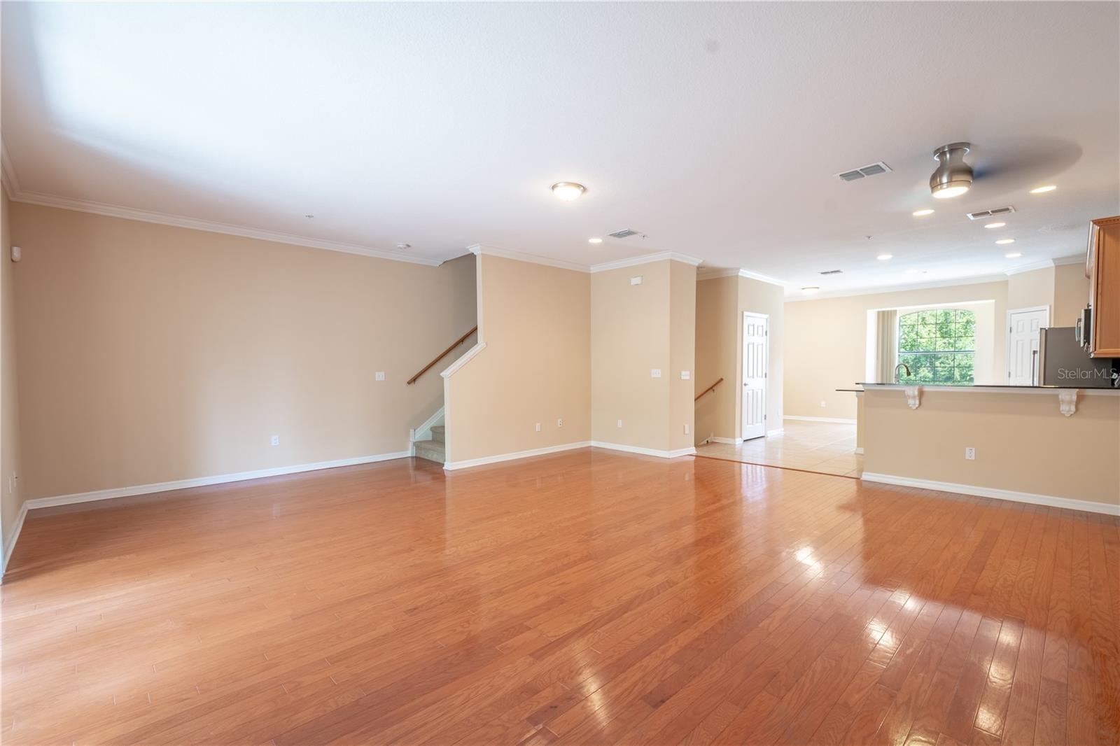 The spacious living and dining areas invite you in with their glistening wood floors, a soft neutral color palette, and elegant crown molding. A ceiling fan adds comfort, making this space perfect for relaxing or entertaining in style.