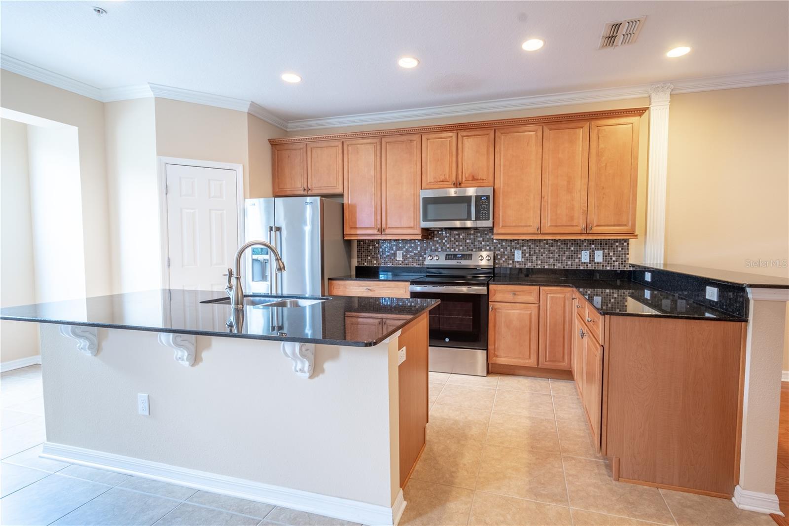 Recessed lighting dances a top the stunning granite countertops, complemented by an artistic tile backsplash.