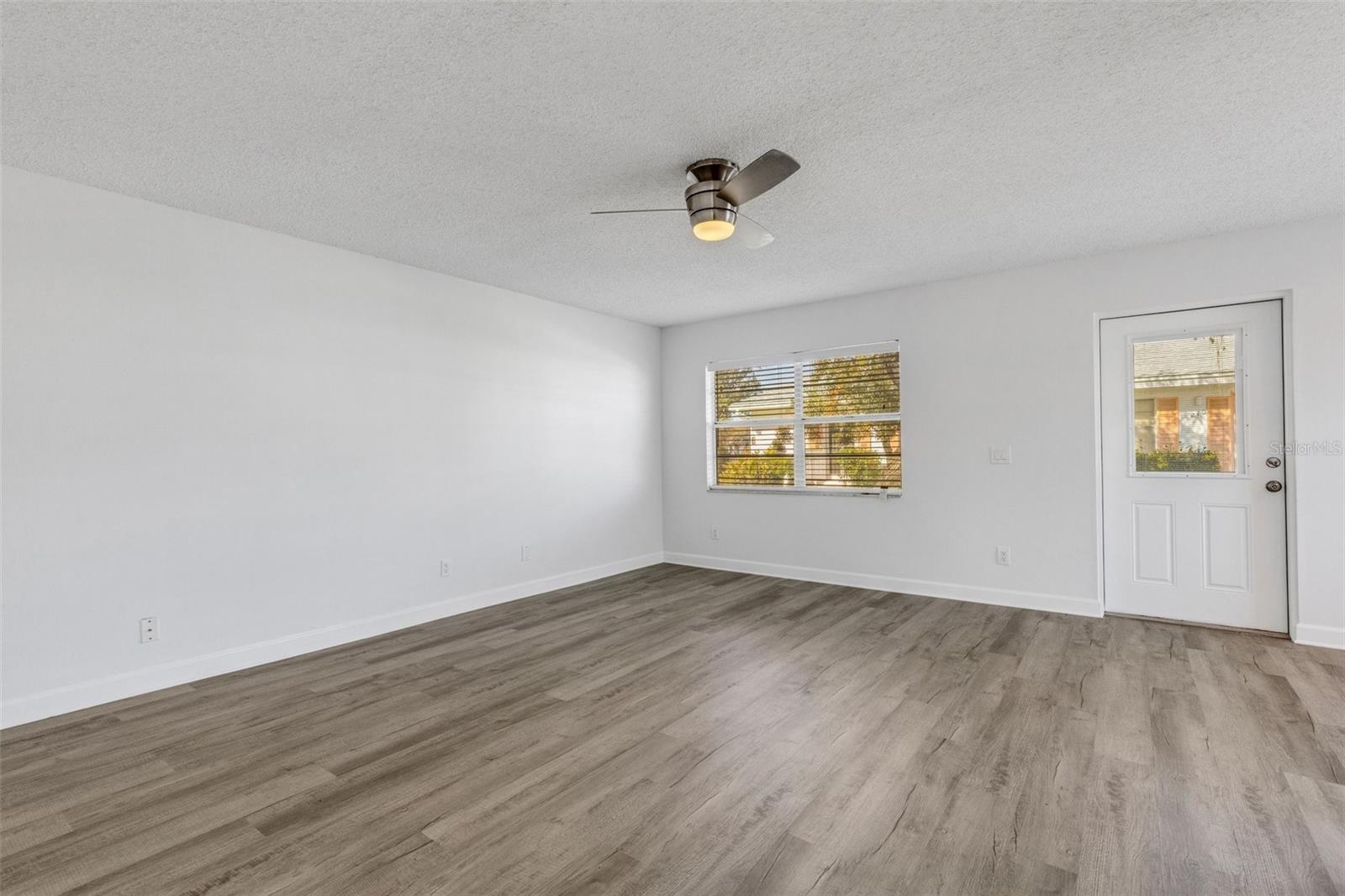 Large spacious living room with new paint, new flooring, new ceiling fan.