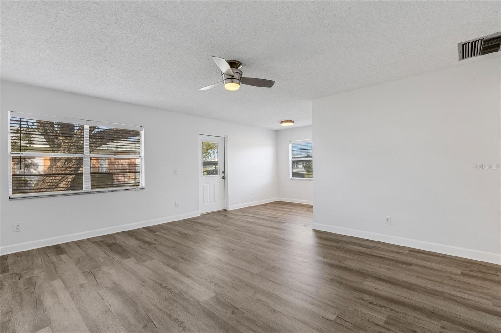 Large spacious living room with new paint, new flooring, new ceiling fan.