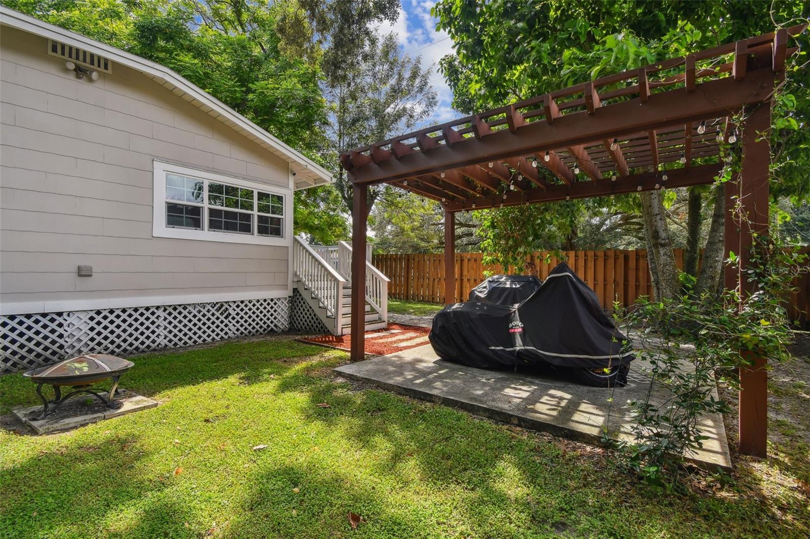 Pergola with Lights and Privacy Fencing Surrounding the Backyard