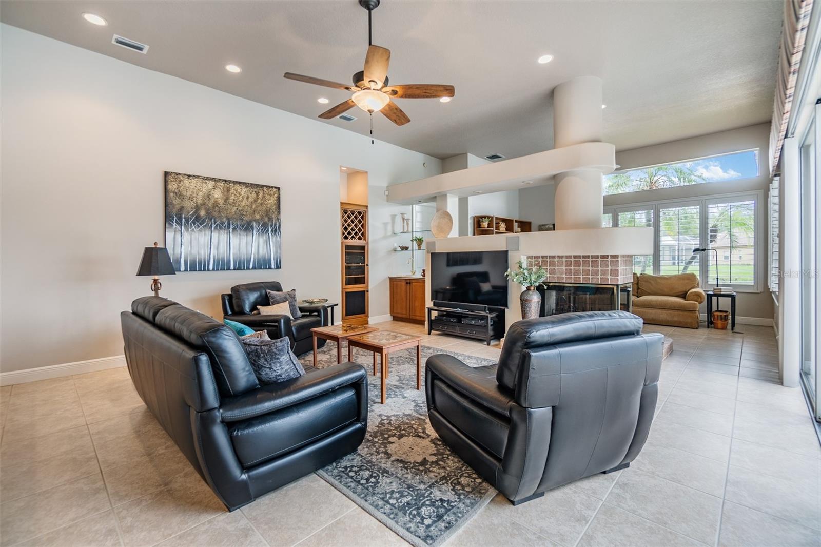 Family room with ceiling fan, Tile Flooring, Fireplace double sided,  overlooking the pool/spa and water view.