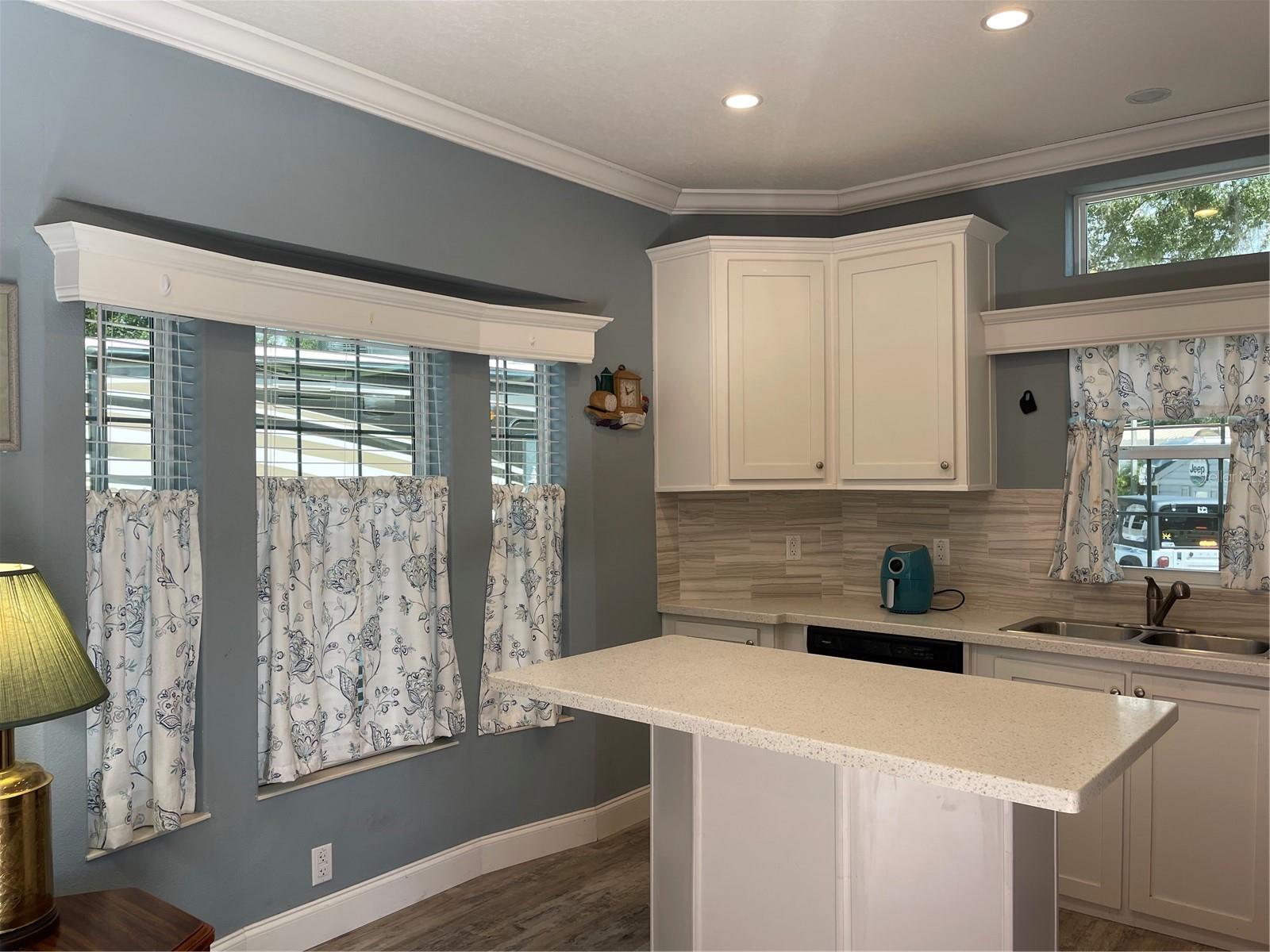 Bay window in kitchen has curtains and blinds