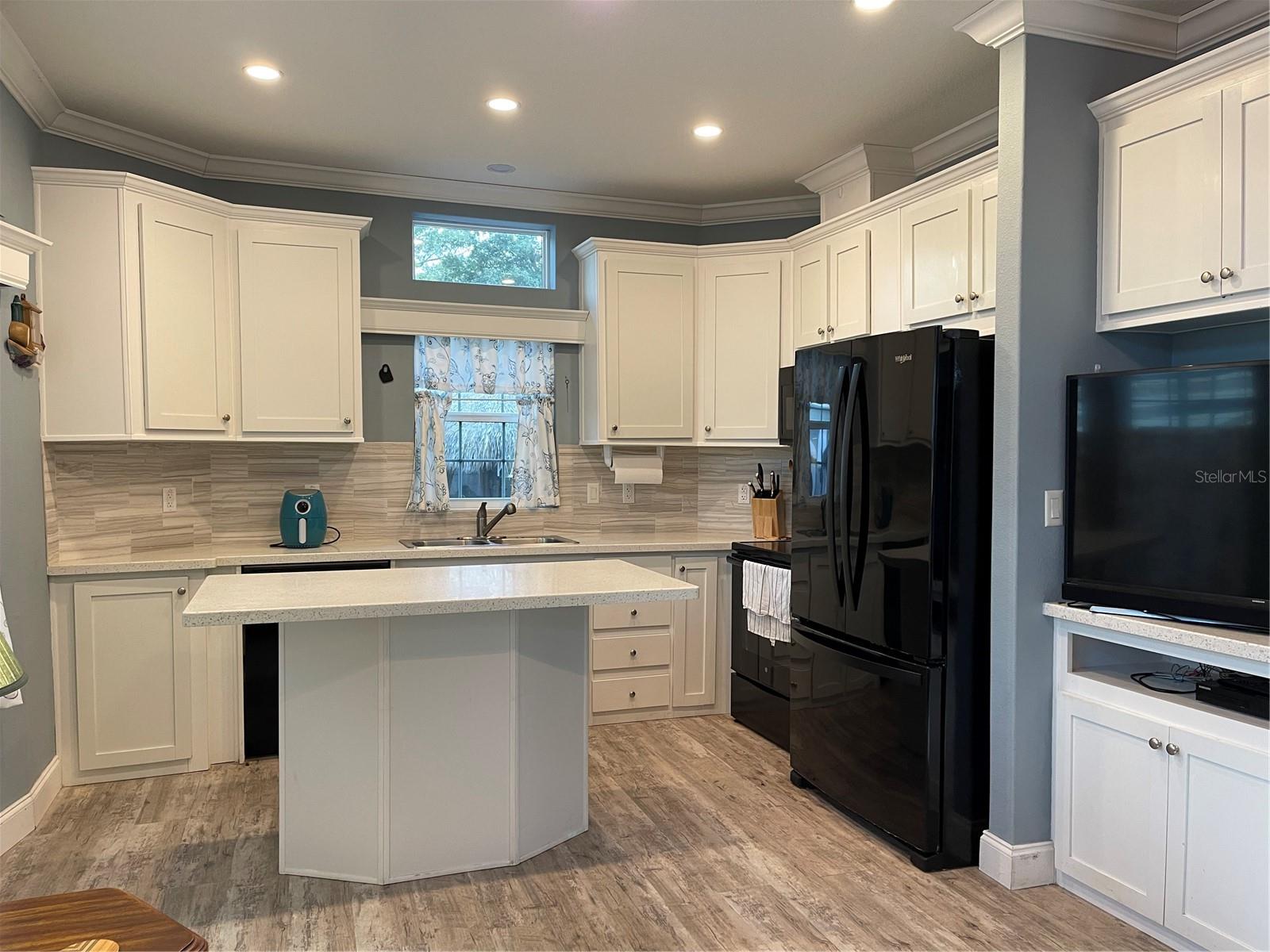 Crown molding and recessed lighting in the kitchen with plenty of cabinets