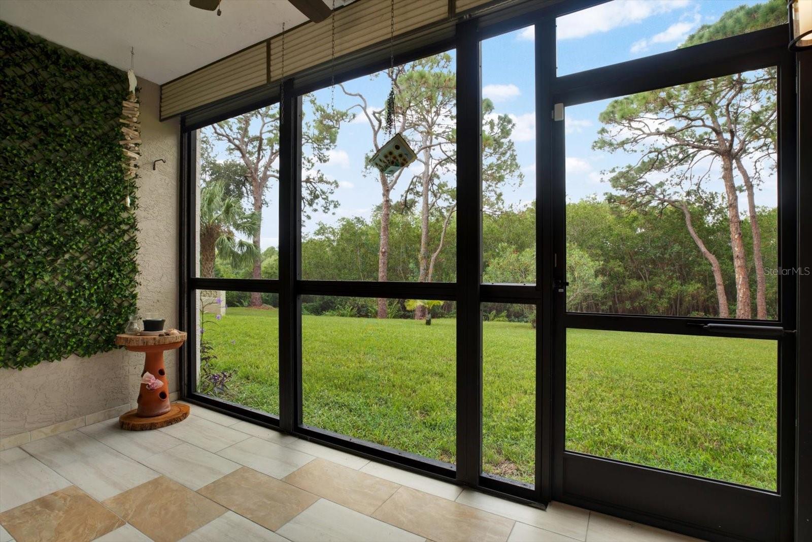 Screened in patio WITH hurricane shutters overlooking the trees and greenery