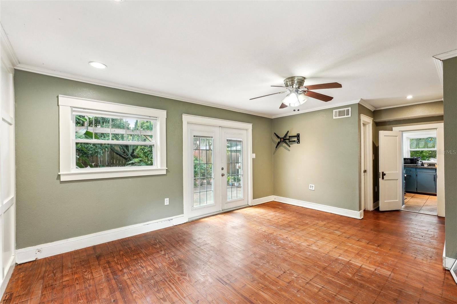 Primary bedroom - french doors lead to outdoor slate patio.  Floors have been stripped to original wood floors ready for your finish touch.