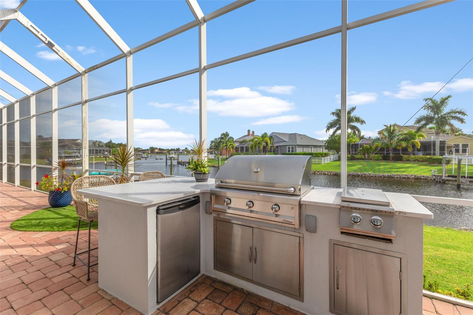 Outdoor kitchen with view of water, pool over beautiful pavers