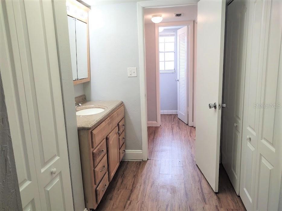 Vanity area with linen closet on left and clothing closet on right. Door to bath and water closet