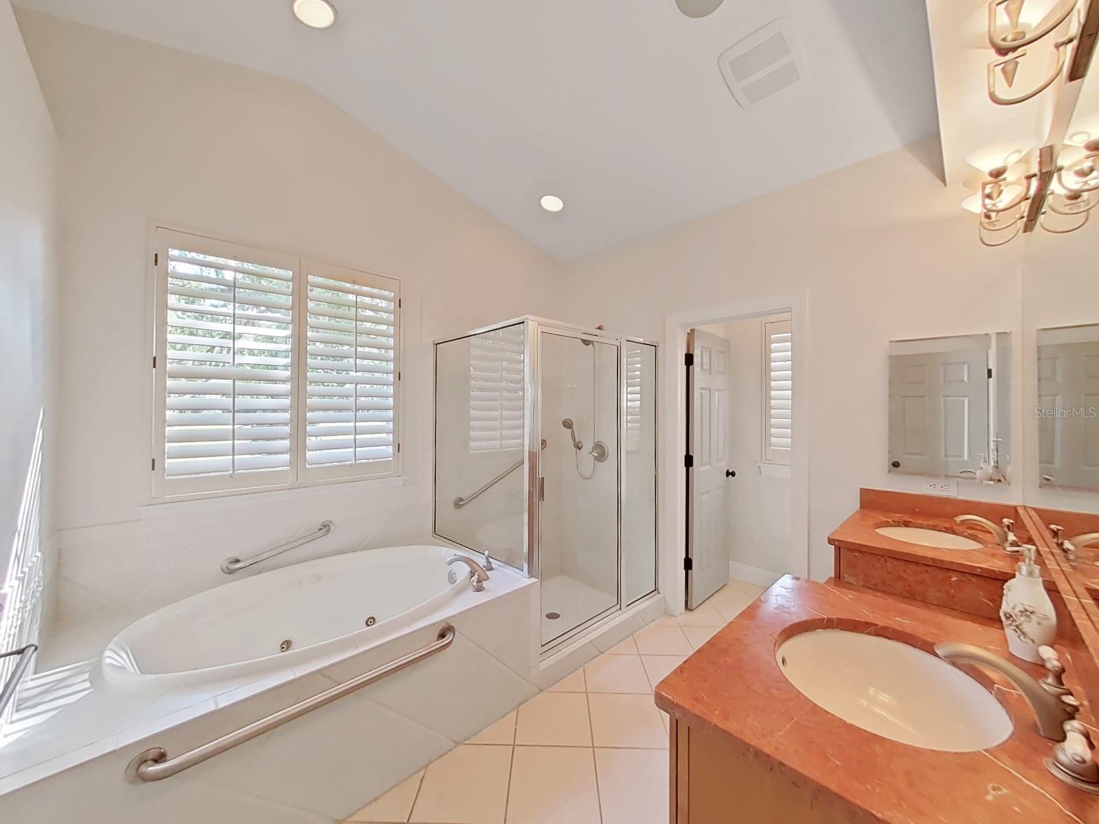 Master bath with jetted tub and dual head shower and double vanity area.