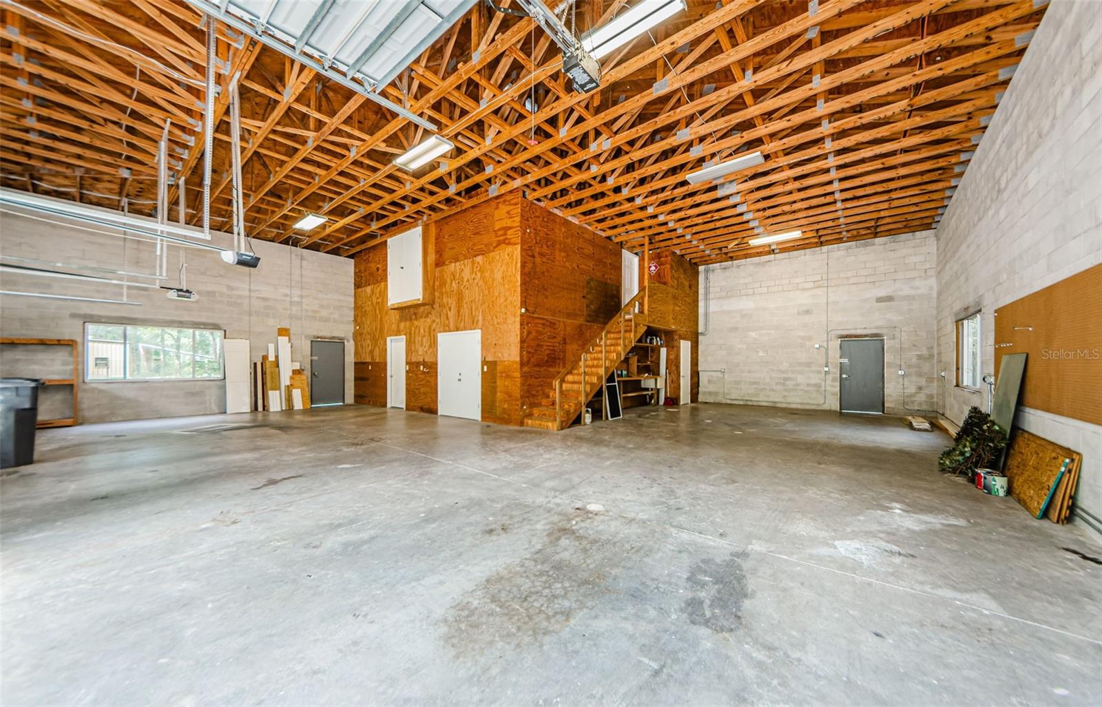 Interior of Garage. The upper white doors open into the Studio apartment for easy furniture moving.The far left white door is the Air Conditioned Office. The Right lower double door is the Storage closet. The stairs lead to the studio apartment. the lower white door near the workbench is a 1/4 bath.