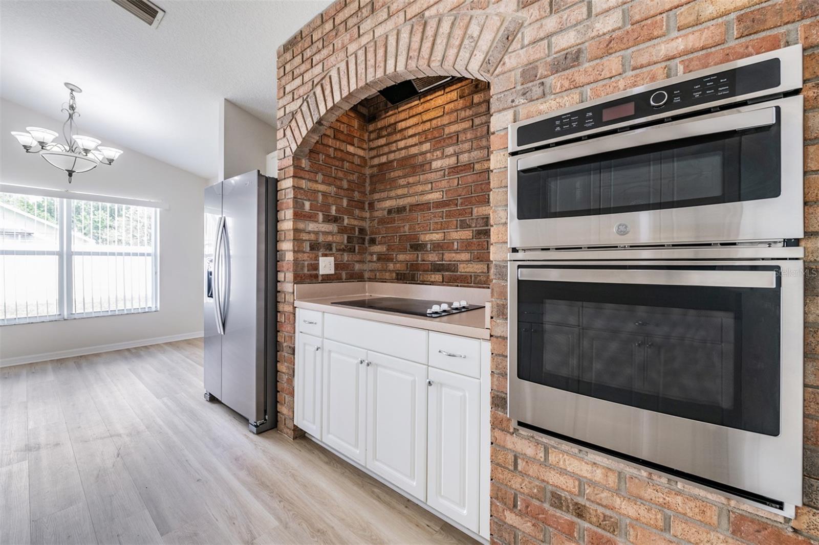 Open Kitchen with cooktop, New refrigerator, oven and microwave.