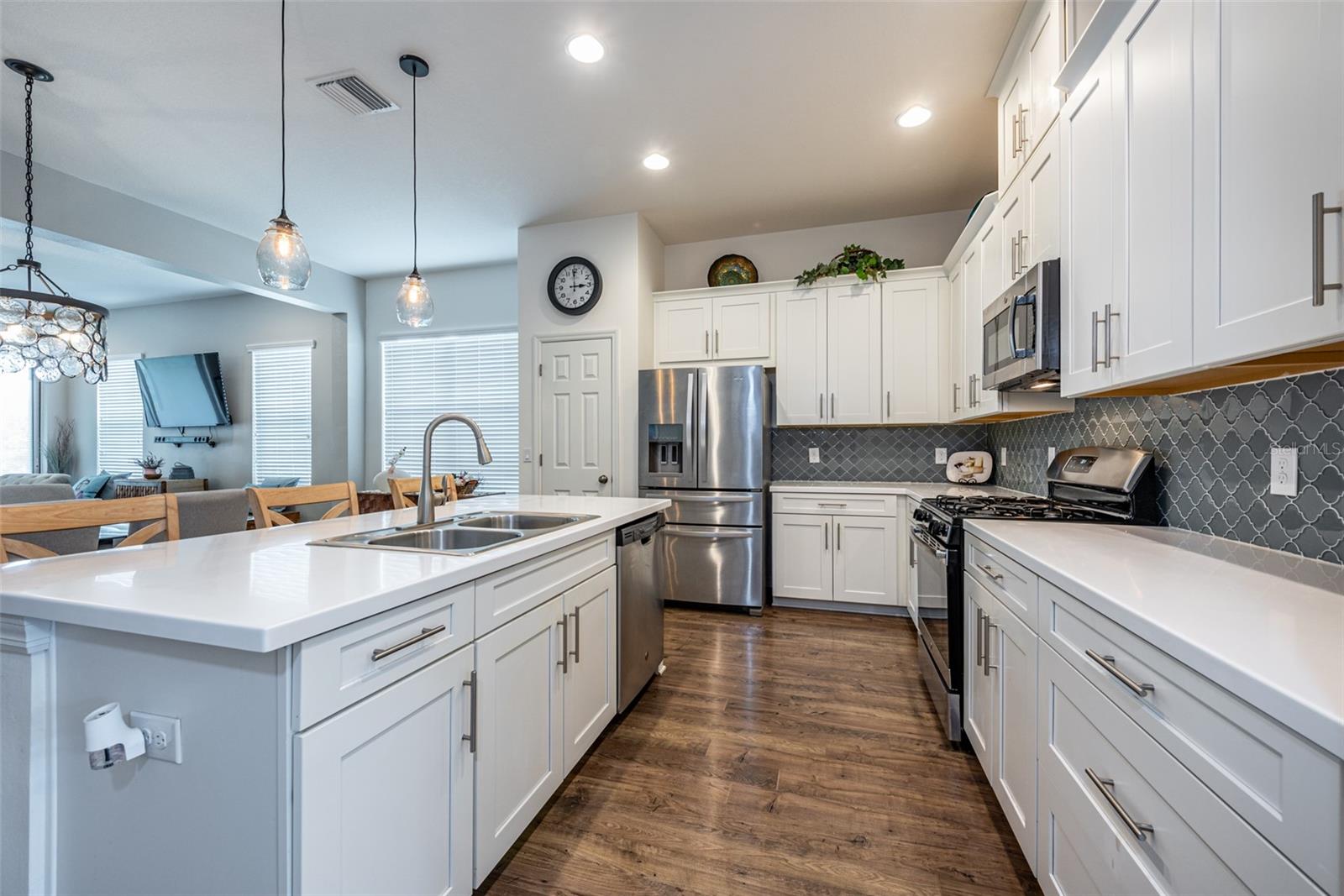 The chef will be thrilled with this meticulously designed kitchen, adorned with 42” white cabinetry, exquisite corian countertops, stylish glass tile backsplash and stainless steel appliances, including a gas oven with a five-burner cast iron stove.