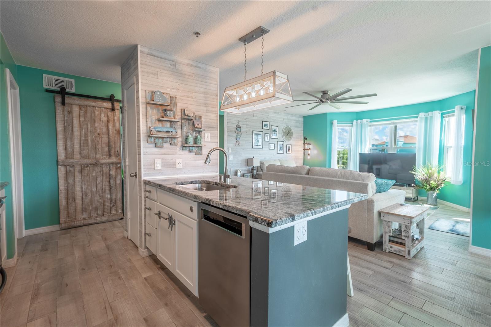 The kitchen island features a 5-bulb, coastal industrial chandelier with a wood-plank accent wall.