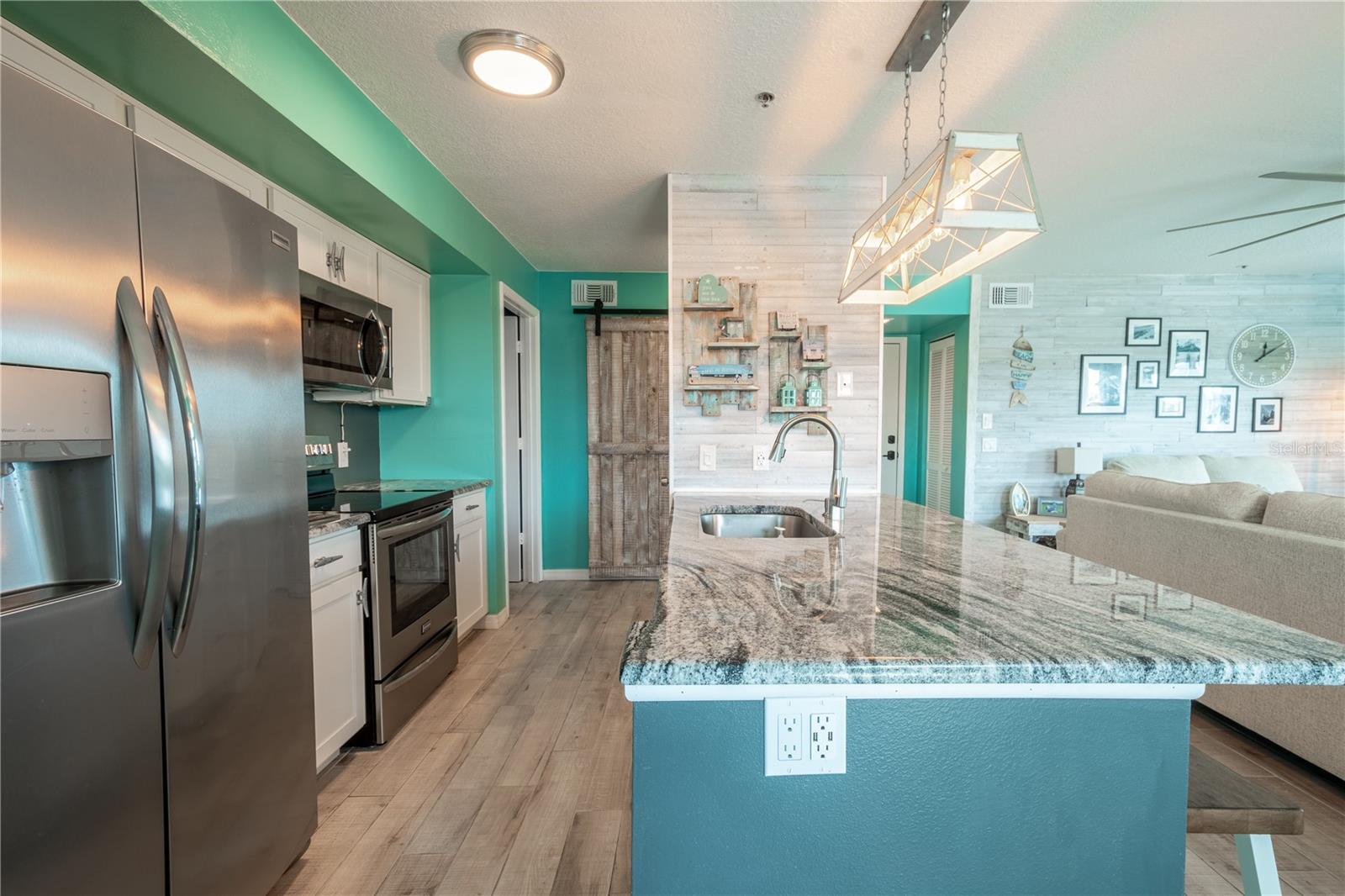 The kitchen features a breakfast bar with granite counter top, stainless steel sink with with pull-down sprayer and wood plank, porcelain tile floors.