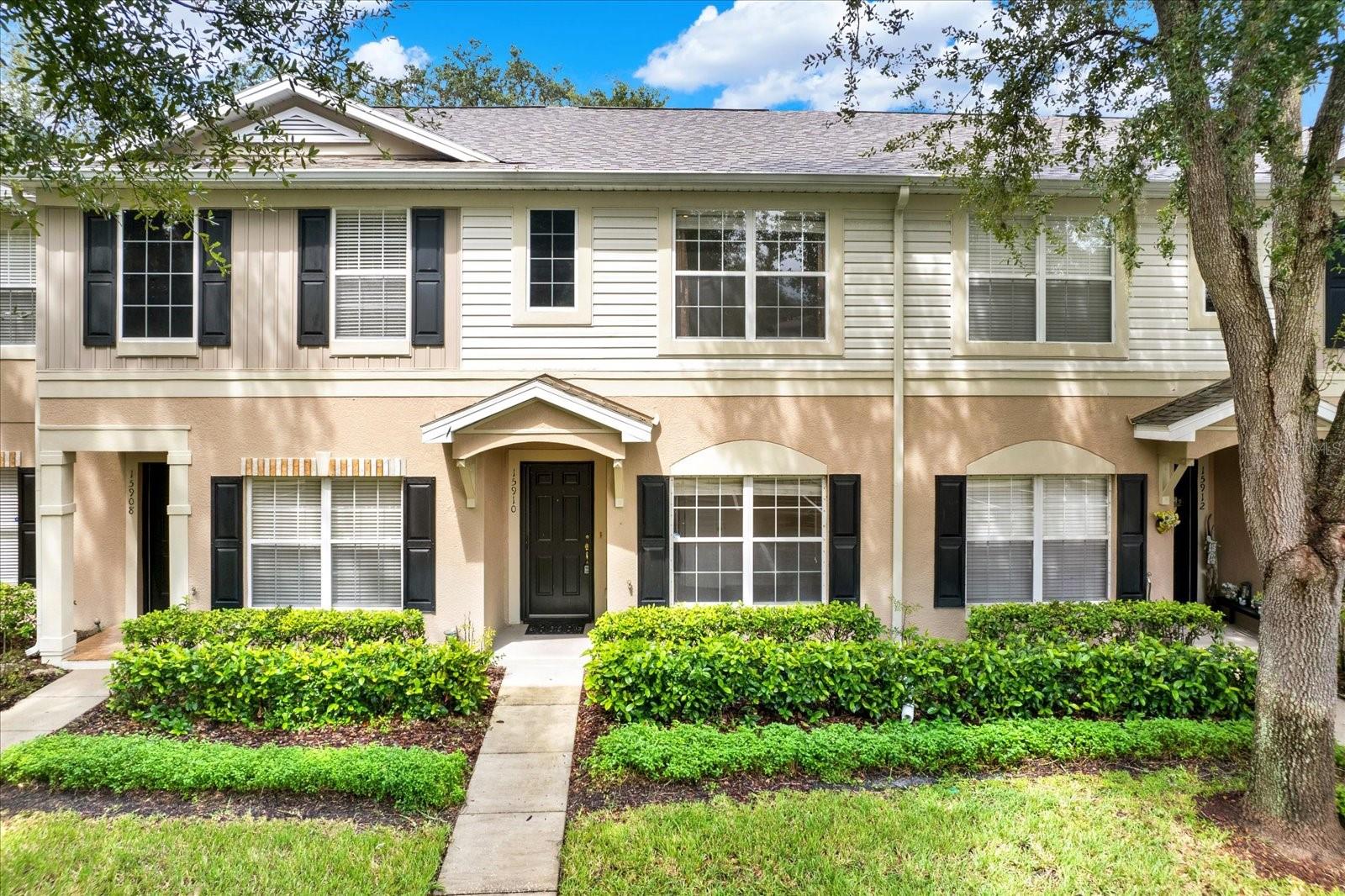 The front of the townhouse is a blend of modern and classic architectural design. The facade is clean and symmetrical, featuring large, energy-efficient windows that contrasts beautifully with the light-colored stucco exterior. A small, well-kept front garden lines the entryway, adding a touch of greenery. The front door is accented with a screen door to allow for those breathy evenings. A narrow porch leads up to the entrance, giving the home a welcoming and refined feel.